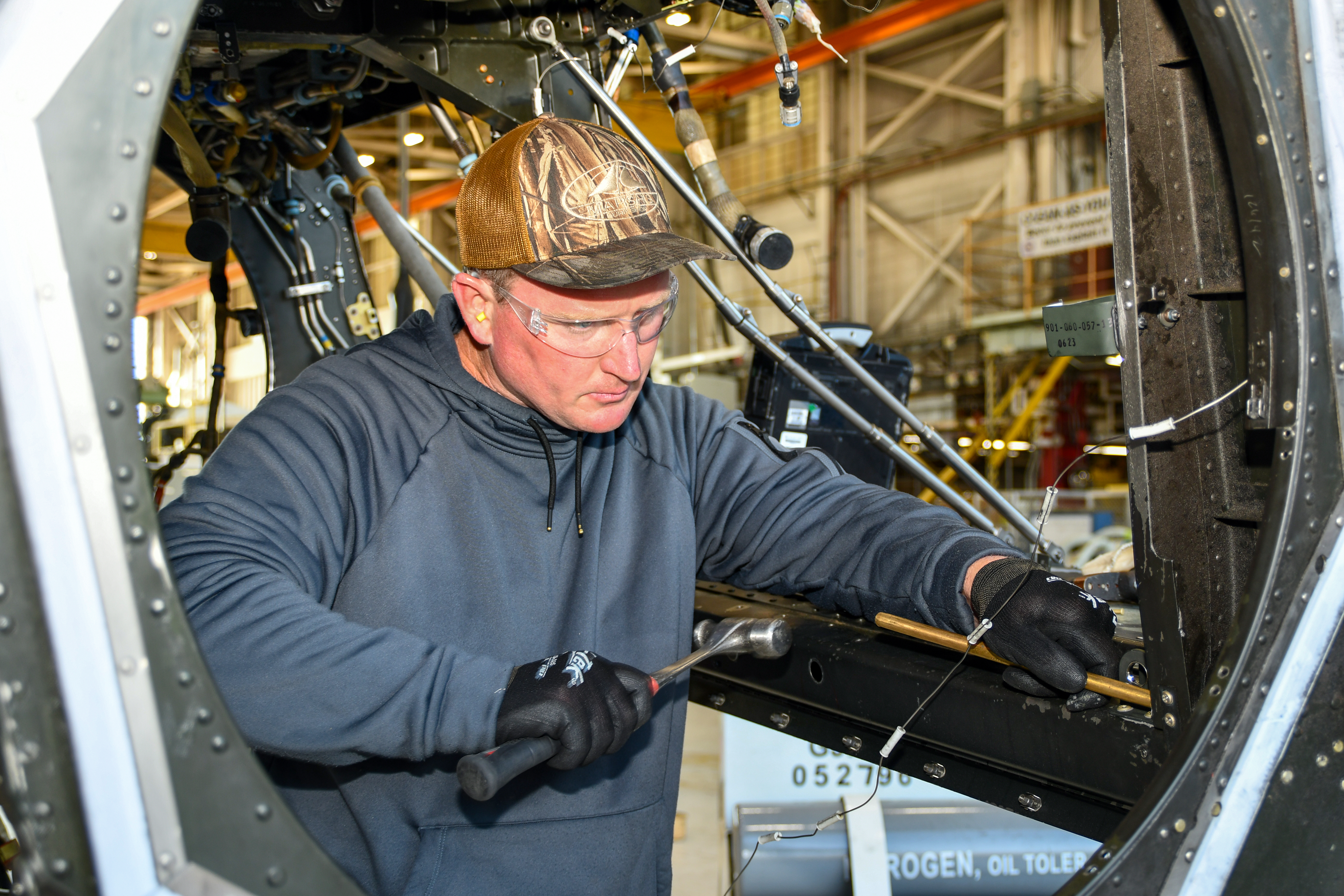 Man using hammer to work on metal aircraft frame