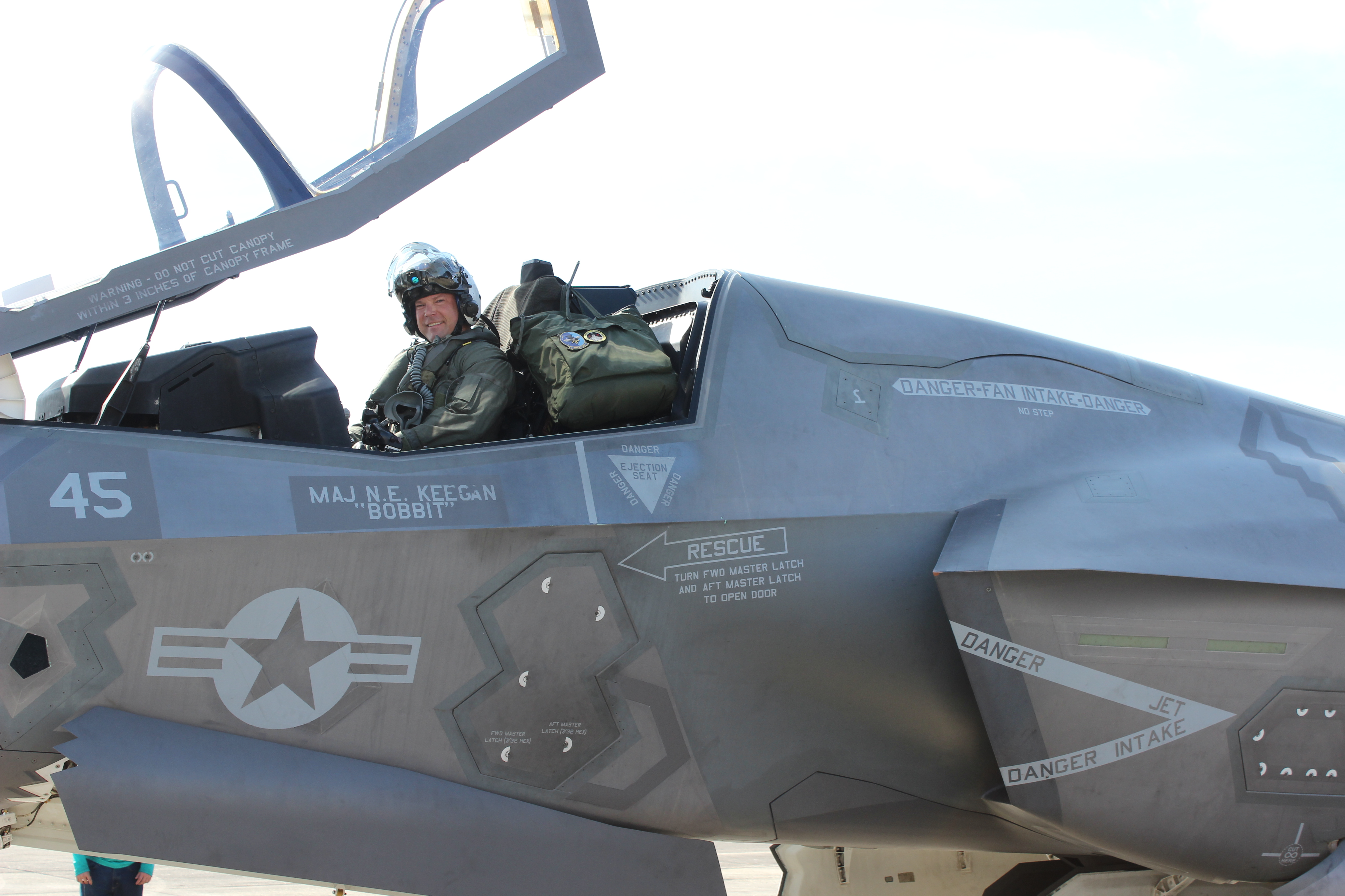 Pilot sits in F-35B Lightning II cockpit with canopy up.