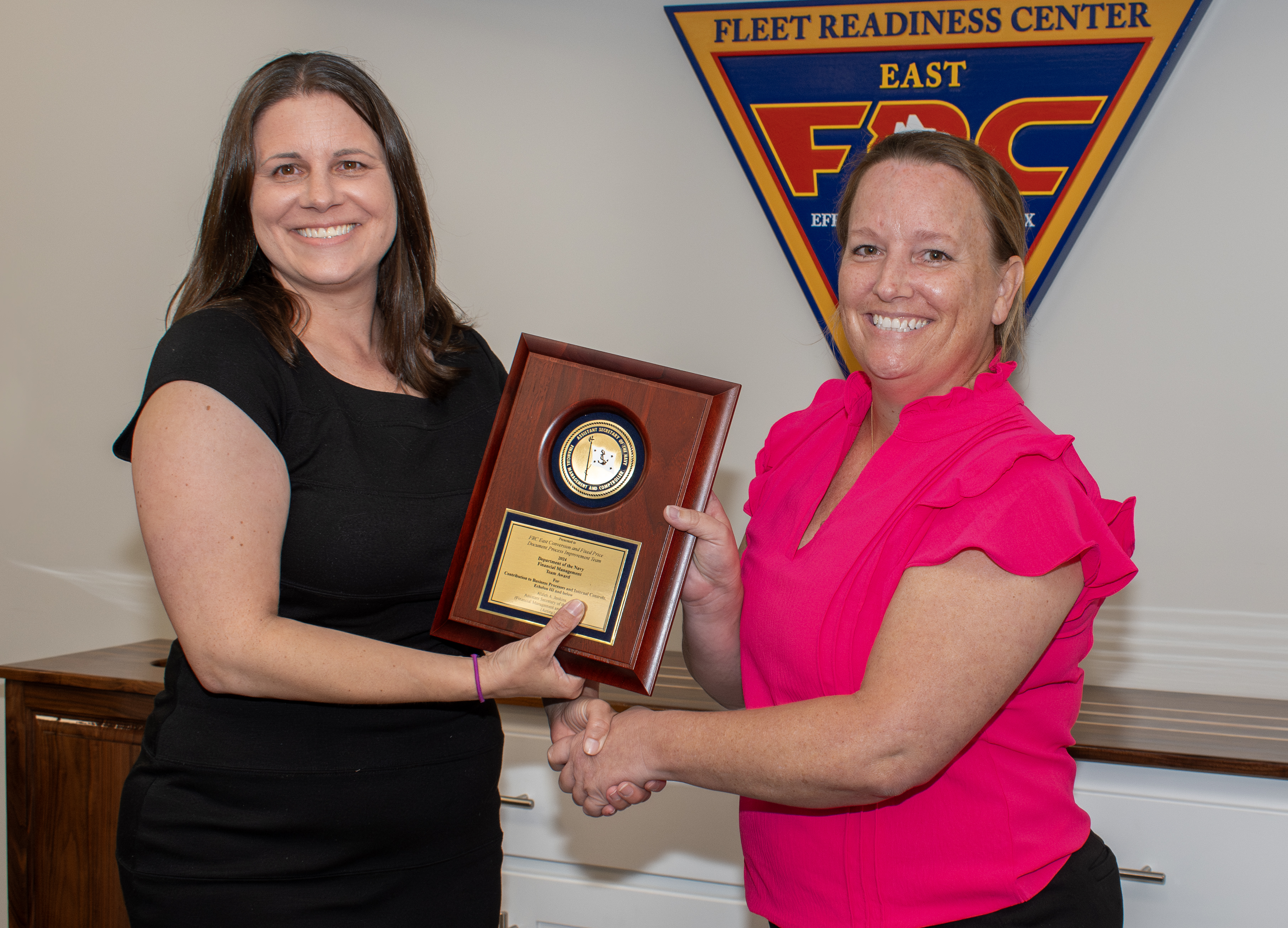 Two women post for photo while holding award plaque