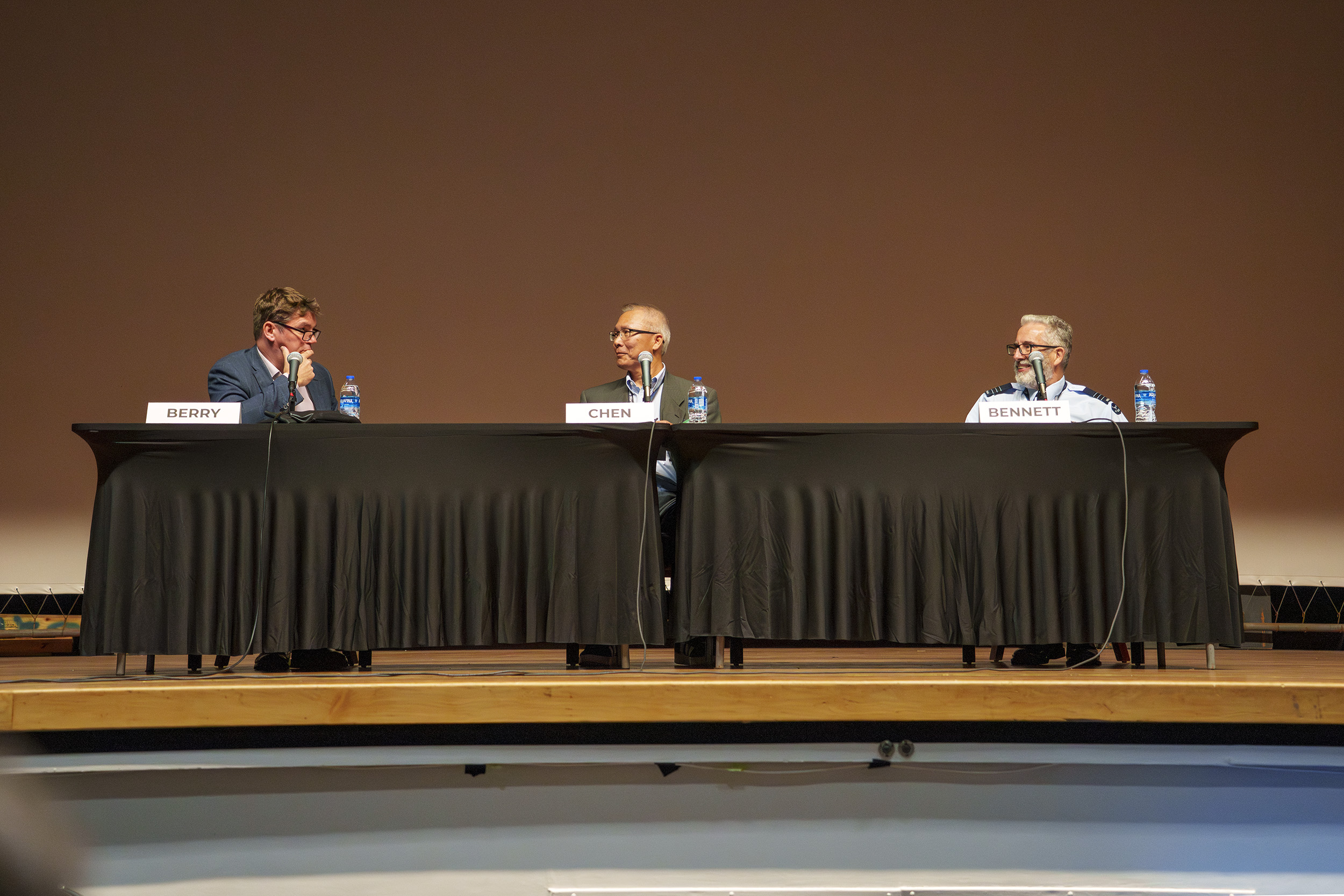Royal Air Force Air Commodore Steve Berry (left), commandant of the United Kingdom's Air and Space Warfare Centre; Dr. Andrew Chen (center), chief engineer of spectrum dominance at Naval Air Warfare Center Weapons Division; and Royal Australian Air Force Wing Commander Joseph Bennett (right) of the Air Warfare Centre participate in an international panel discussion at Naval Base Ventura County Point Mugu, March 11, 2026. 