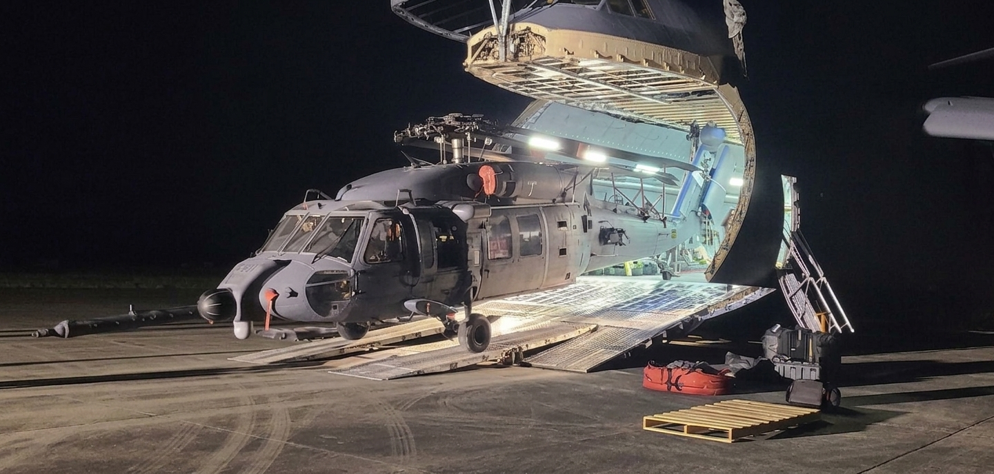 HH-60W helicopter coming out of a C-5 aircraft nose at night 