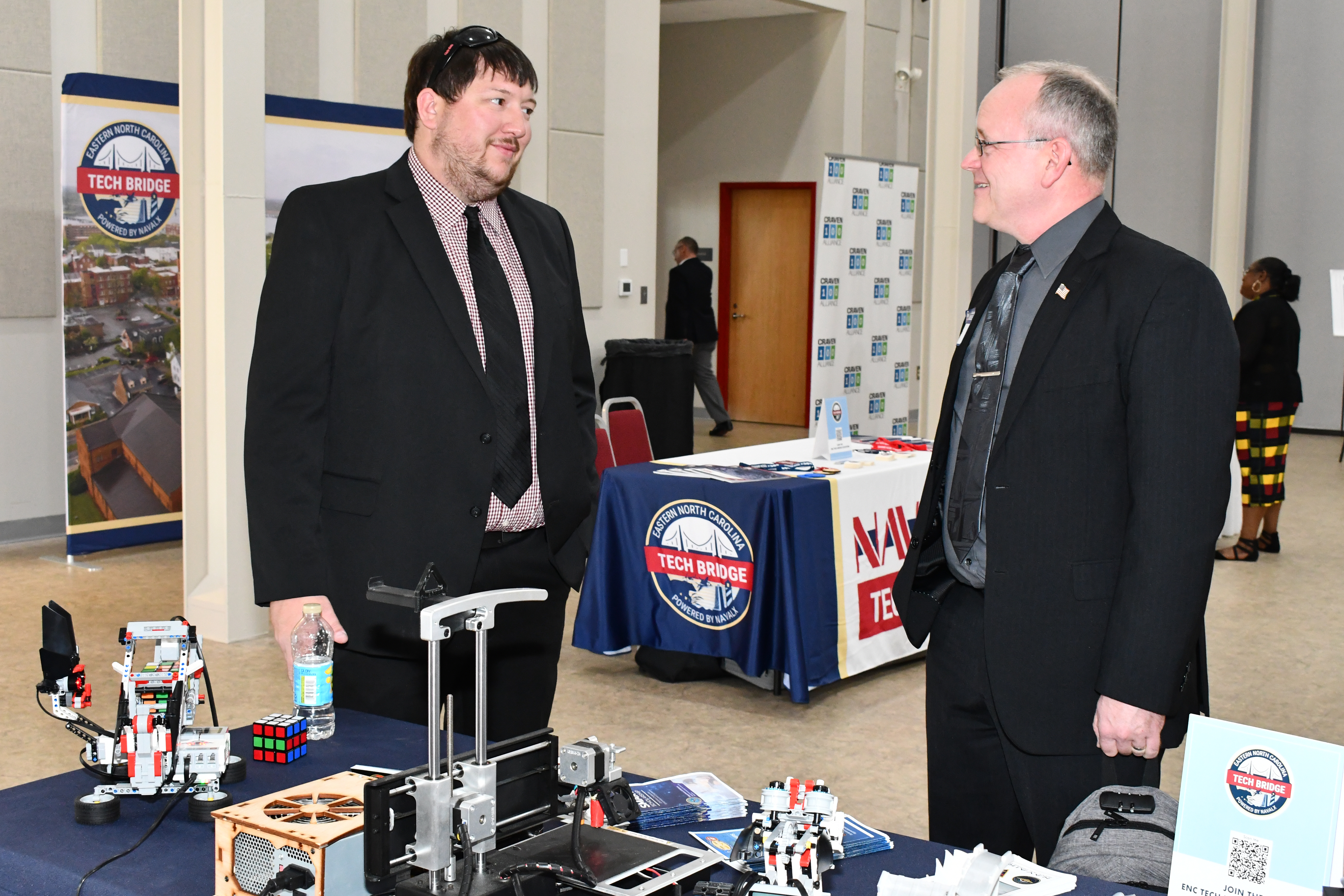 Two men talk in front of expo table