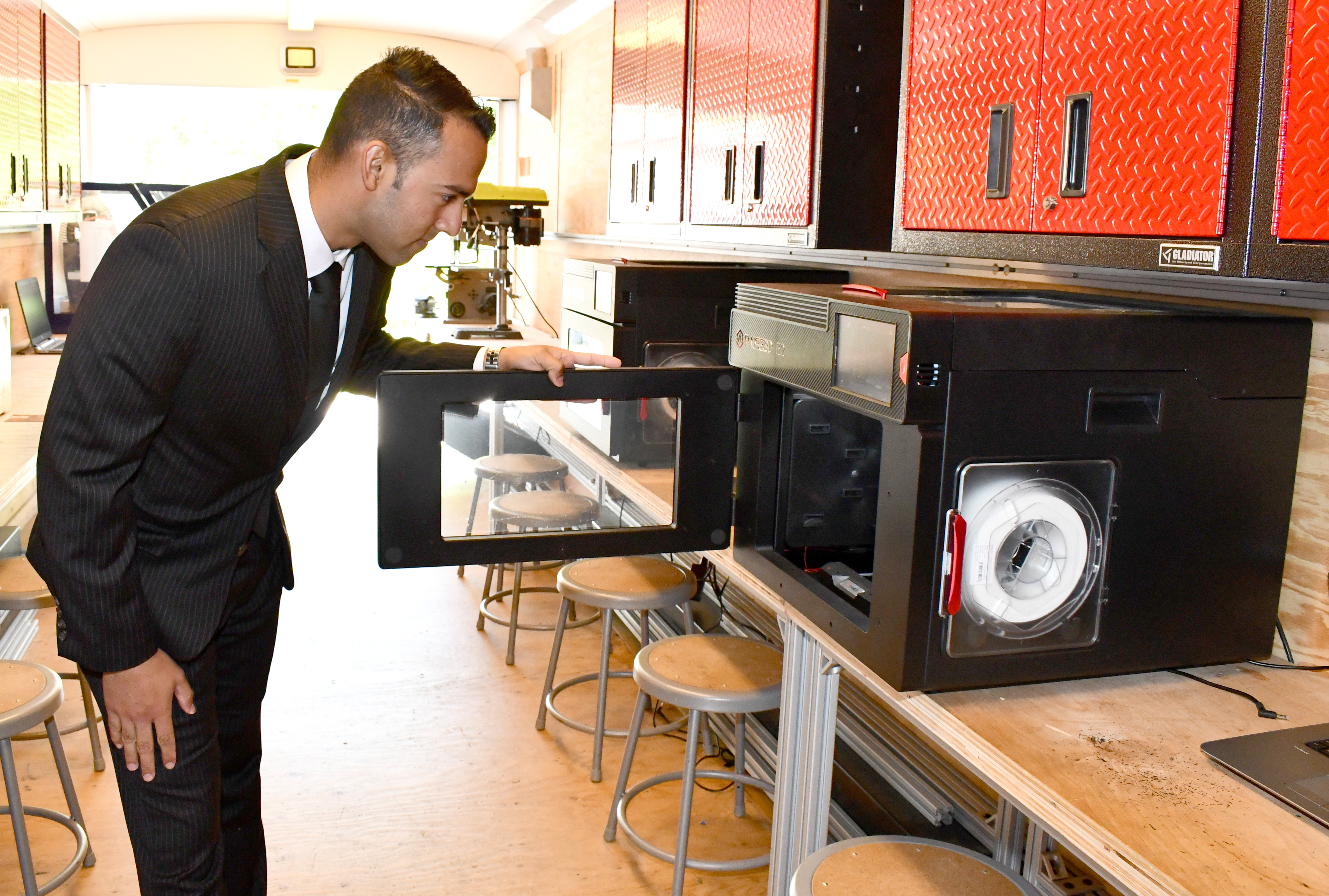 Engineer opens door of 3D printer in mobile lab trailer