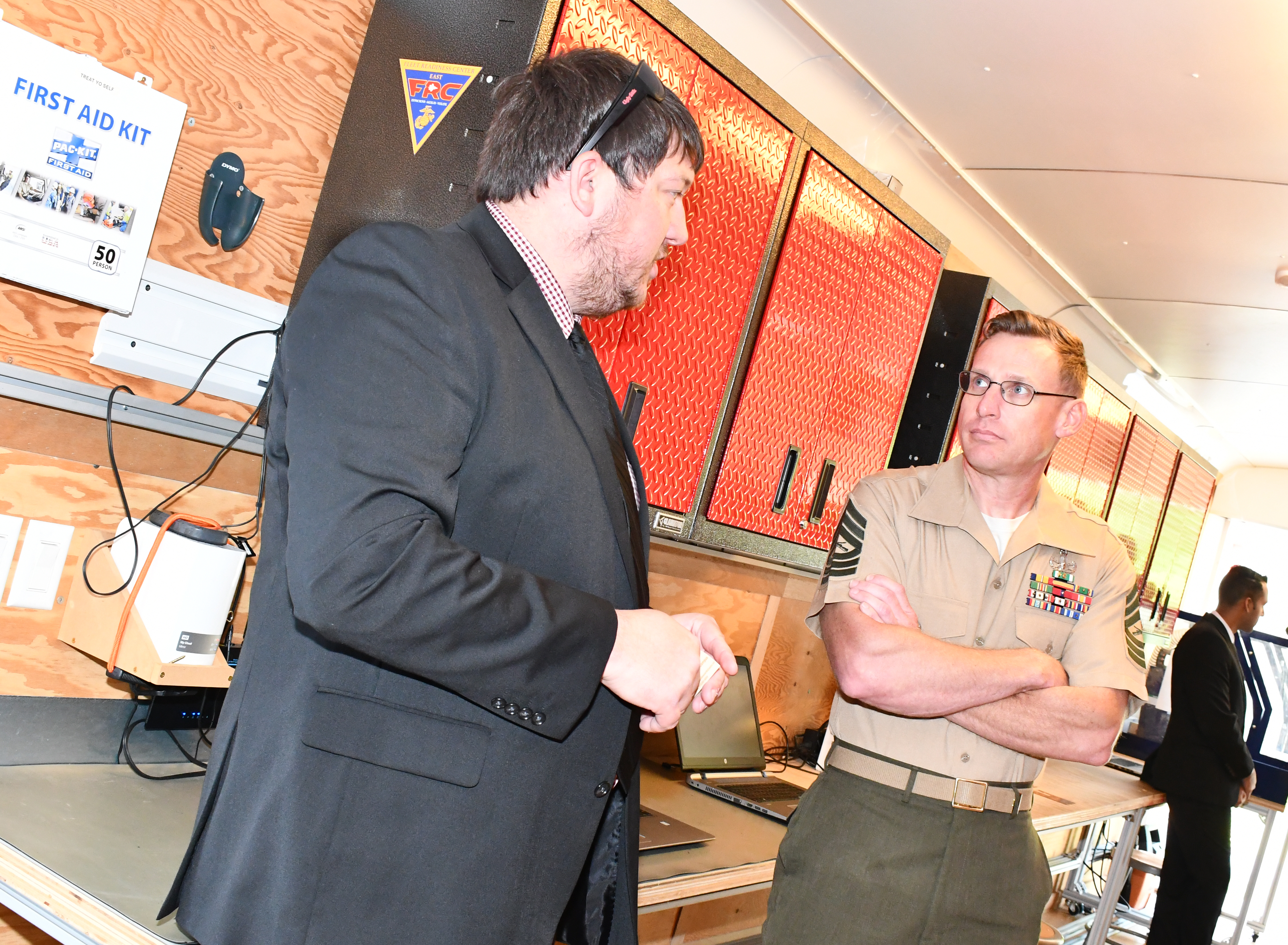 Engineer and Marine hold conversation in mobile fabrication lab trailer
