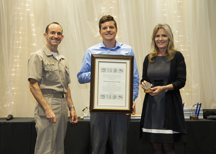 Shawn Higgins accepts the Dr. William B. McLean Memorial Award from Rear Adm. Scott Dillon, NAWCWD commander, and Joan Johnson, NAWCWD executive director, during the 2019 Honorary Awards Ceremony at China Lake on June 25. (U.S. Navy photo by Ryan Smith)