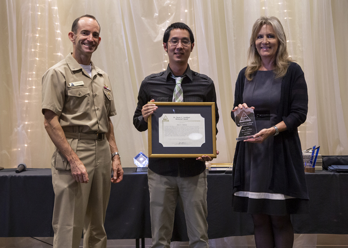 Alex Oshiro accepts the Dr. Twain C. Lockhart Memorial Award from Rear Adm. Scott Dillon, NAWCWD commander, and Joan Johnson, NAWCWD executive director, during the 2019 Honorary Awards Ceremony at China Lake on June 25. (U.S. Navy photo by Ryan Smith)