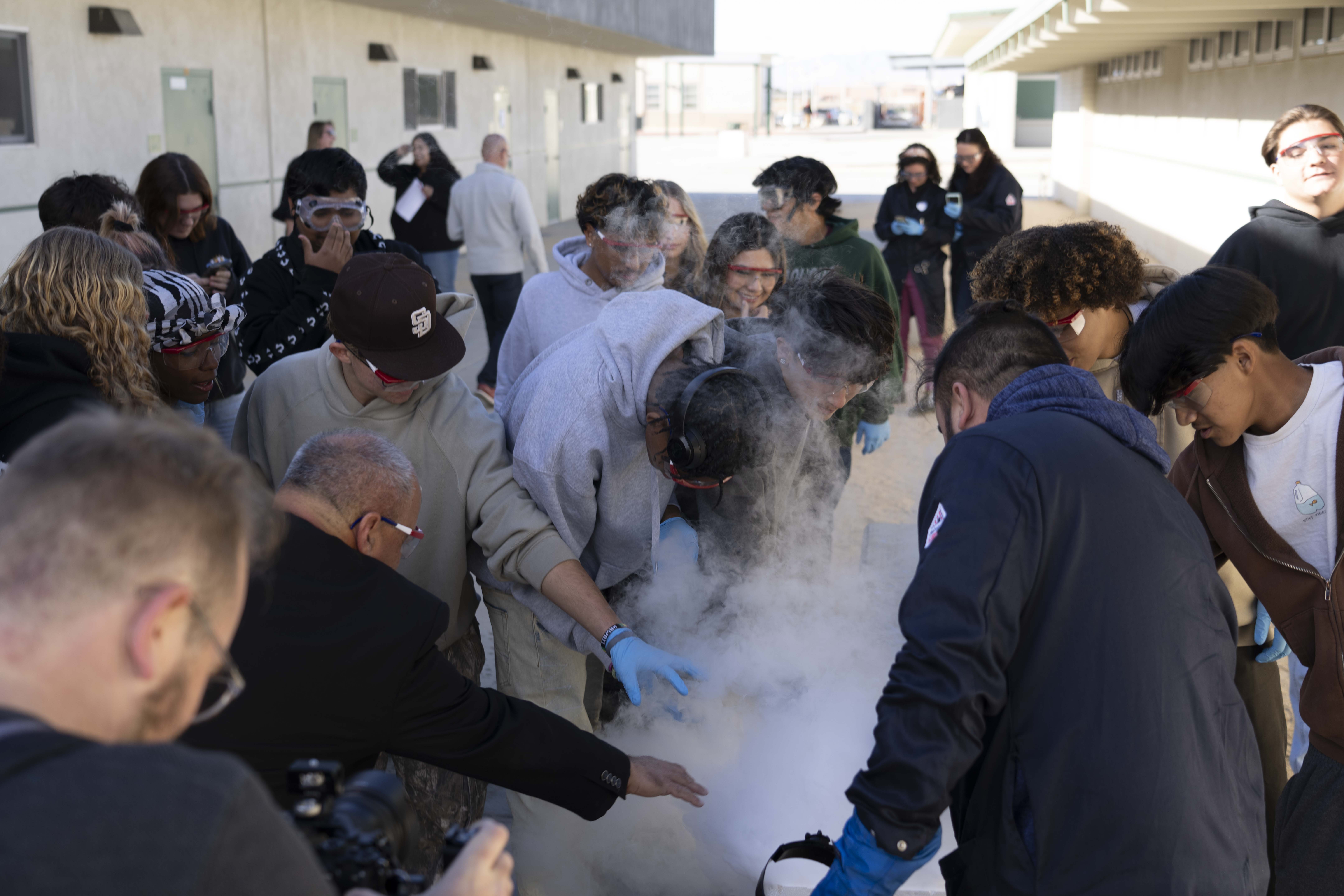 Naval Air Warfare Center Weapons Division Executive Director Dan Carreño (second from left) joins a group of students during a liquid nitrogen experiment performed by NAWCWD Chemist Dr. Patrick Fedick (right) during a Burroughs High School STEM event last fall in Ridgecrest, Calif.  (U.S. Navy photo by Ryan Smith)