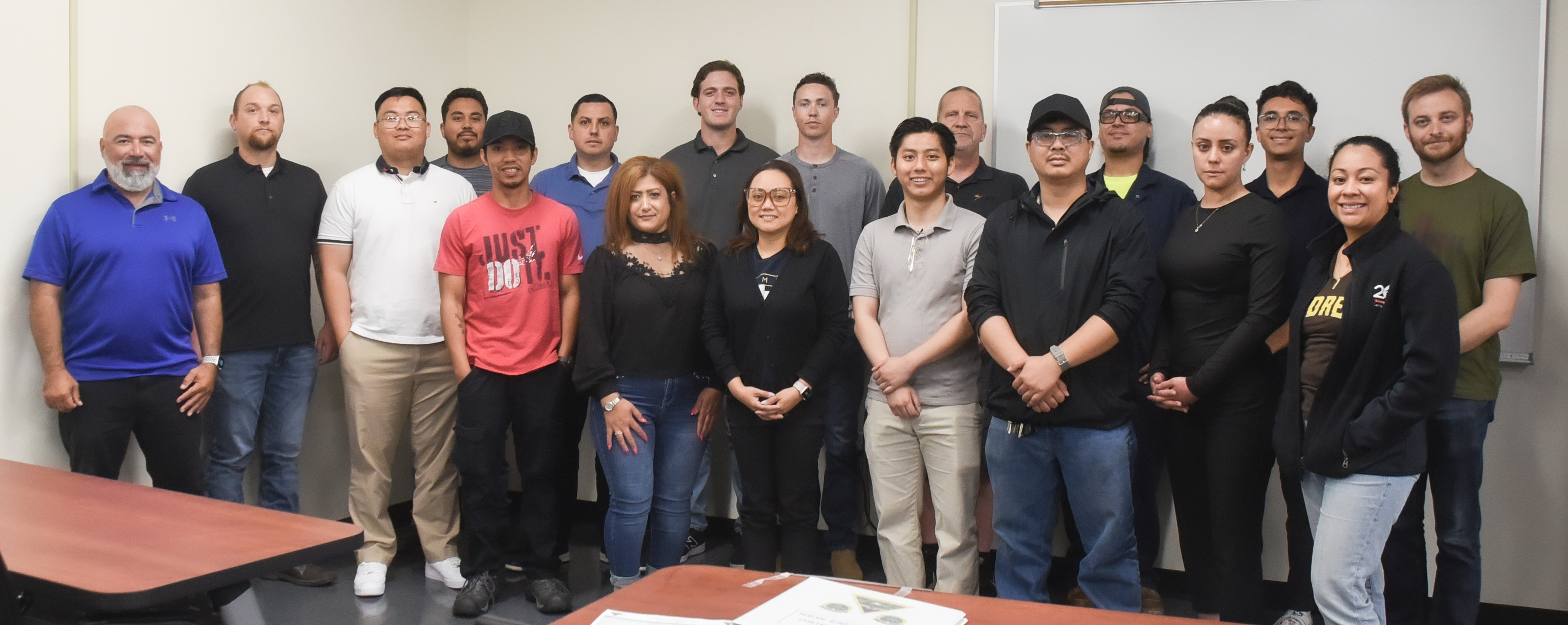 A group of new hired personnel standing and smiling in front of the camera. 