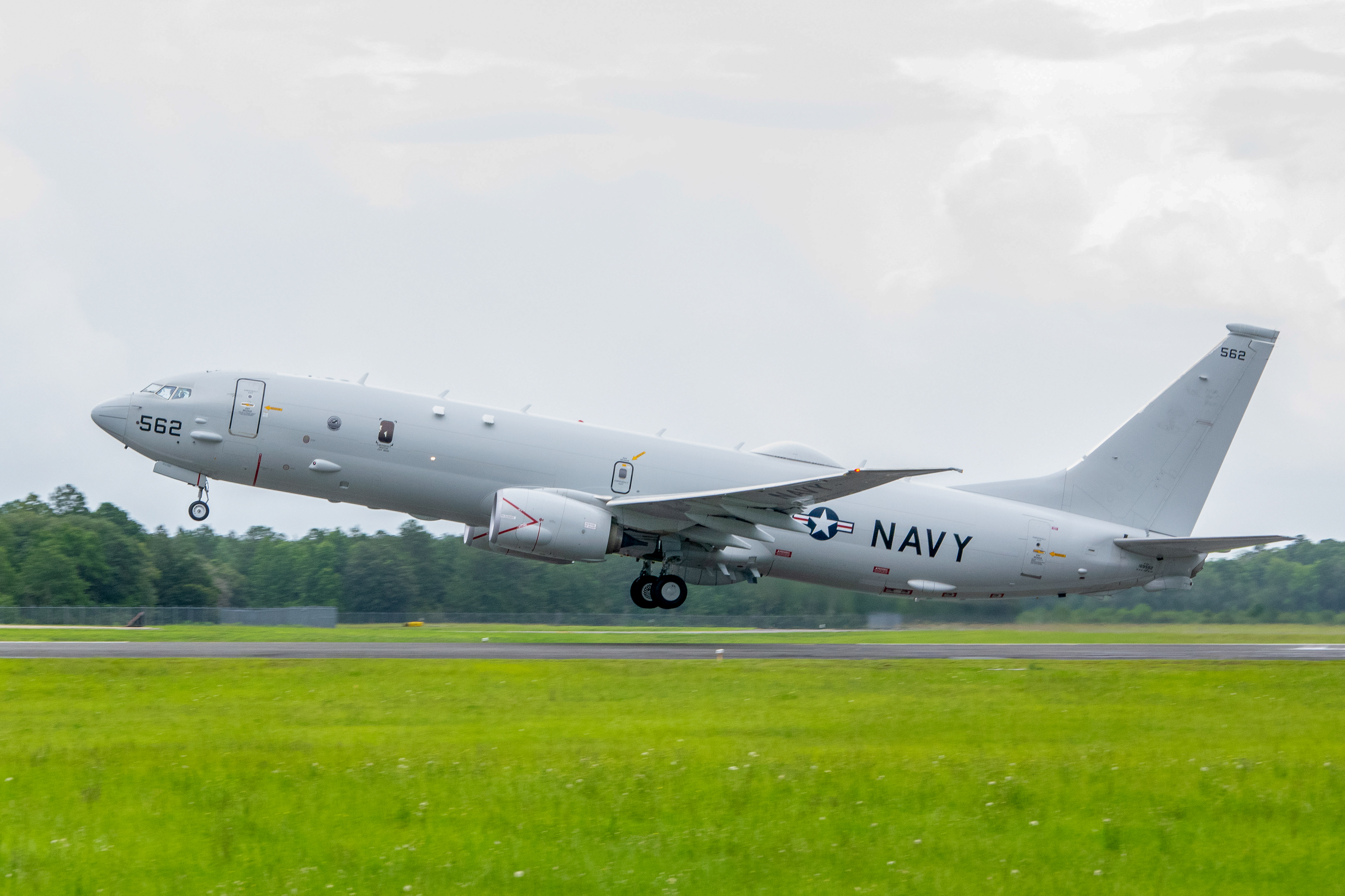 P-8A flies away with green grass in the foregound