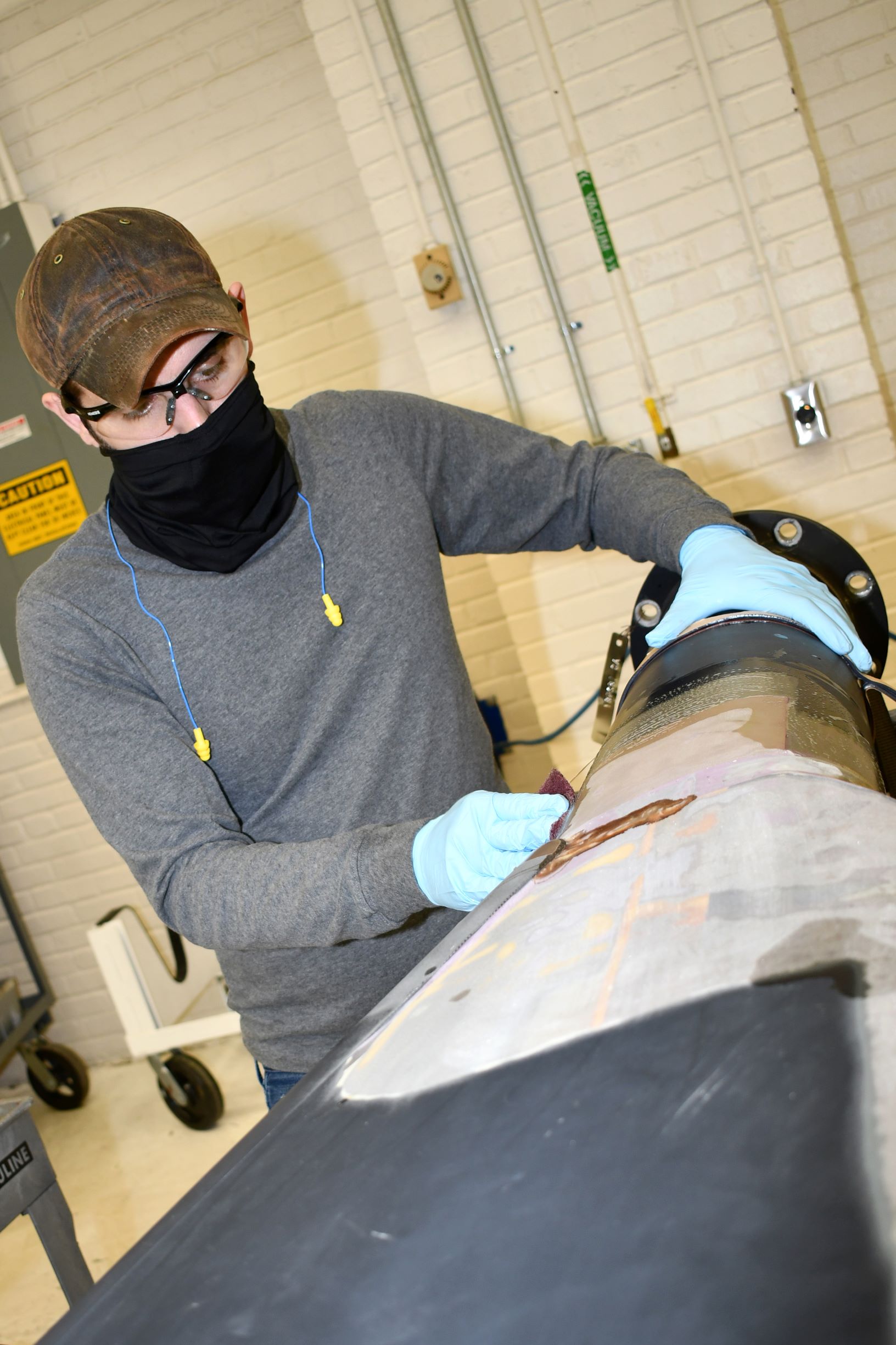 Worker cleans H-53 helicopter rotor blade to prepare for repairs
