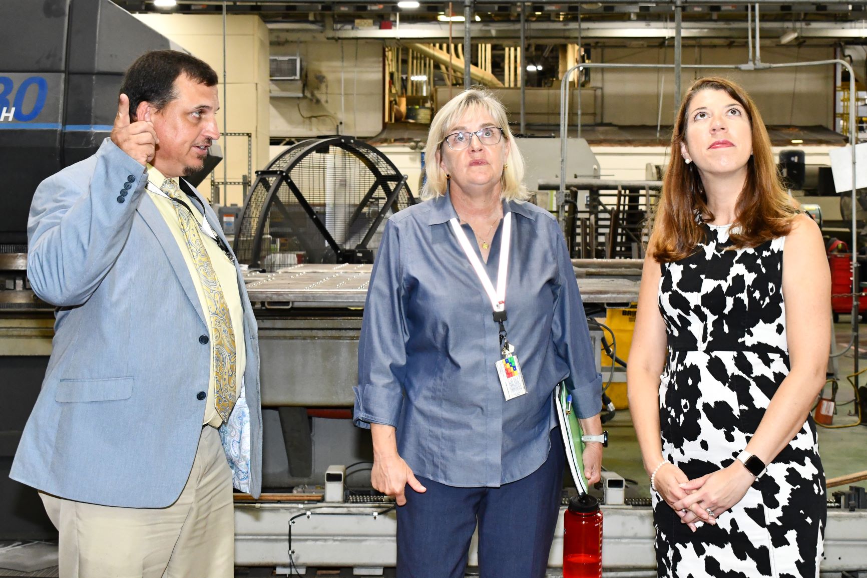 Group of two women and one man look at ceiling in aircraft hangar
