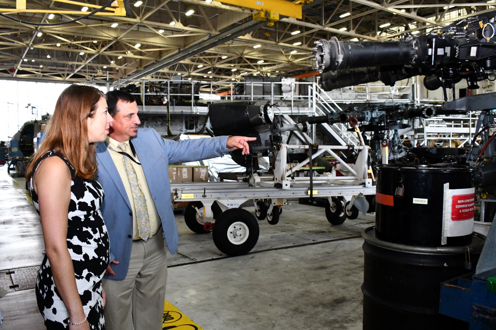 Man points at H-53 rotor head while talking with woman