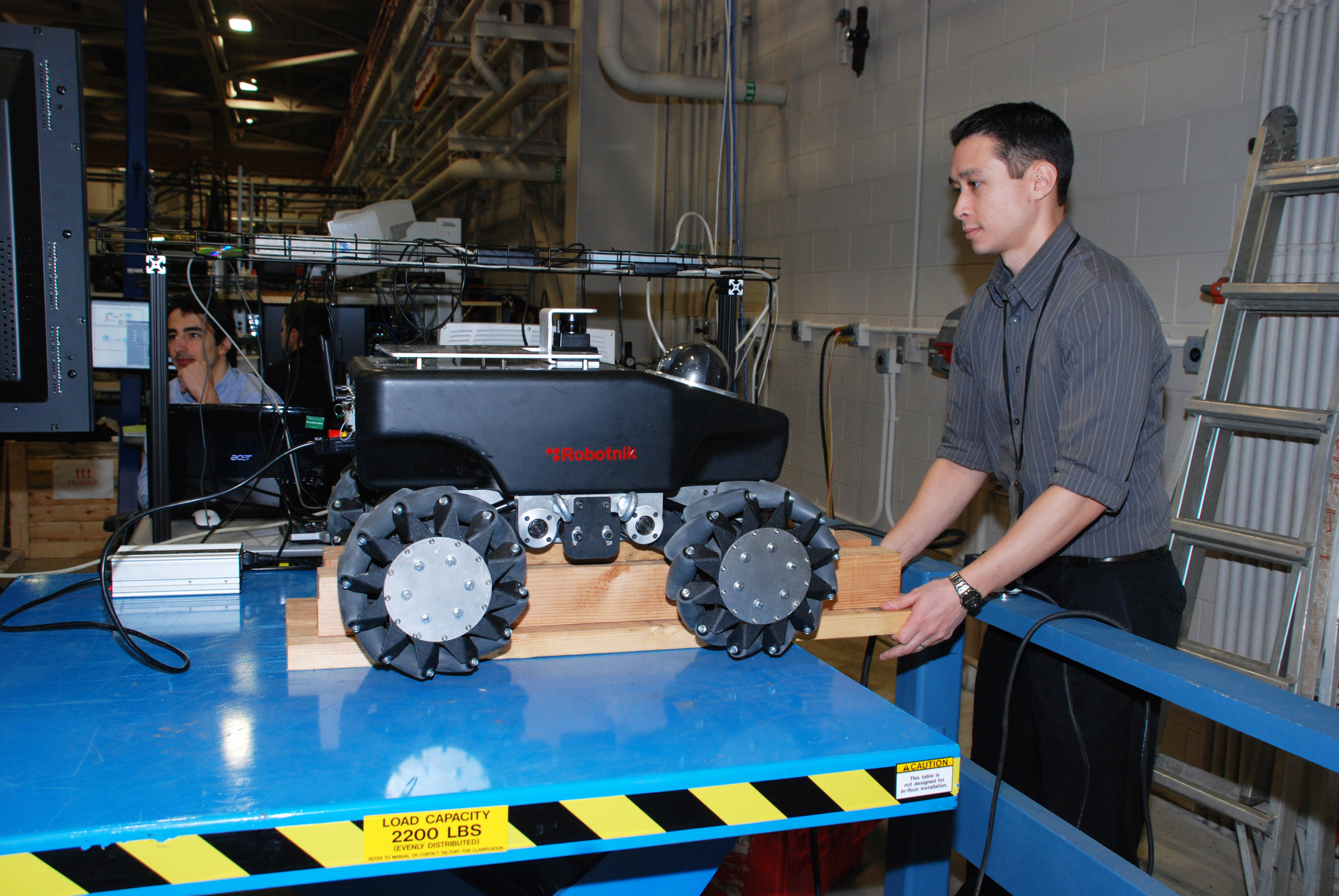 Dr. James Hing moves a robot inside the Robotics and Intelligent Systems lab at Lakehurst