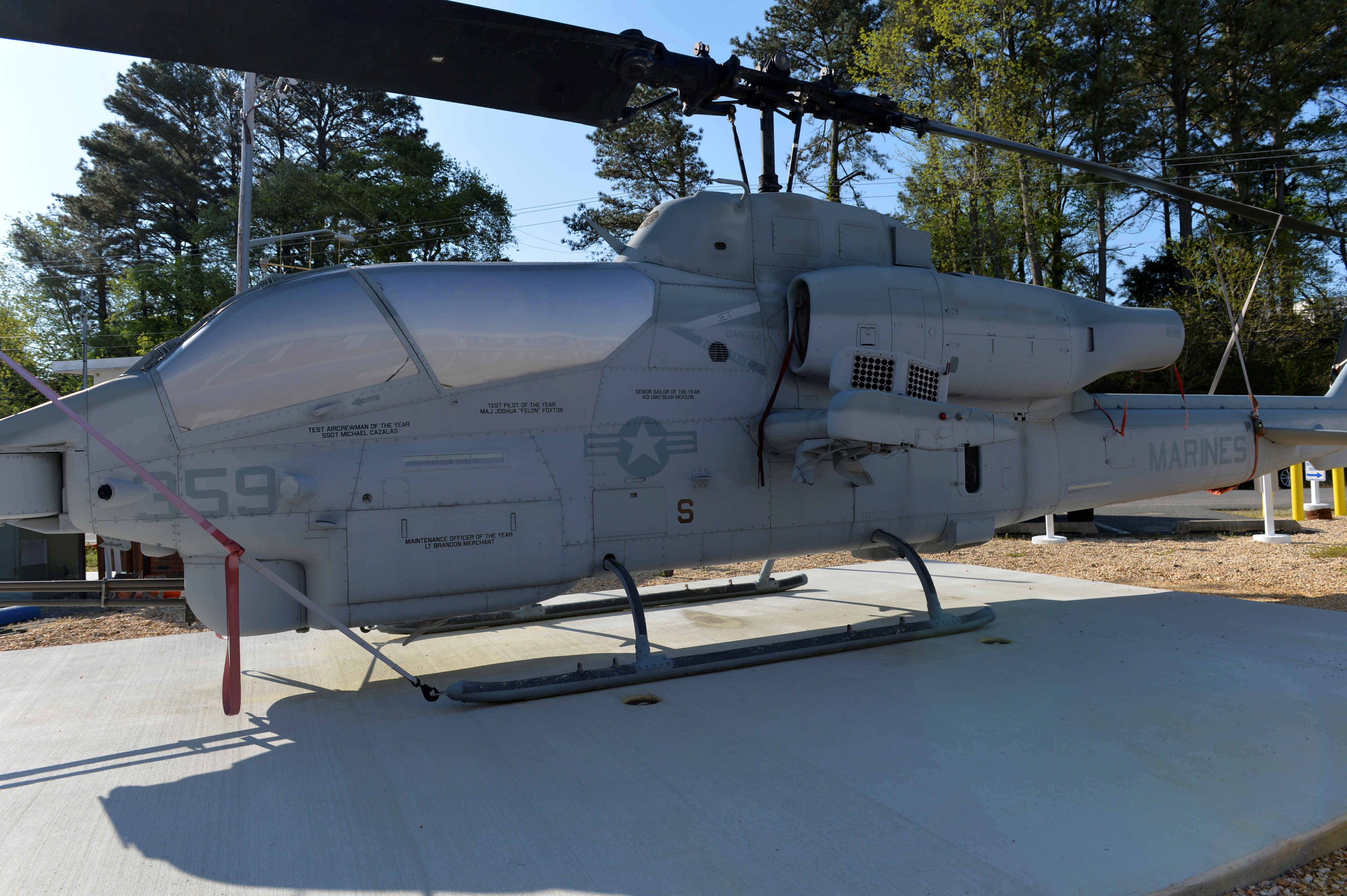 An AH-1W Cobra is displayed in front of an aircraft hangar.