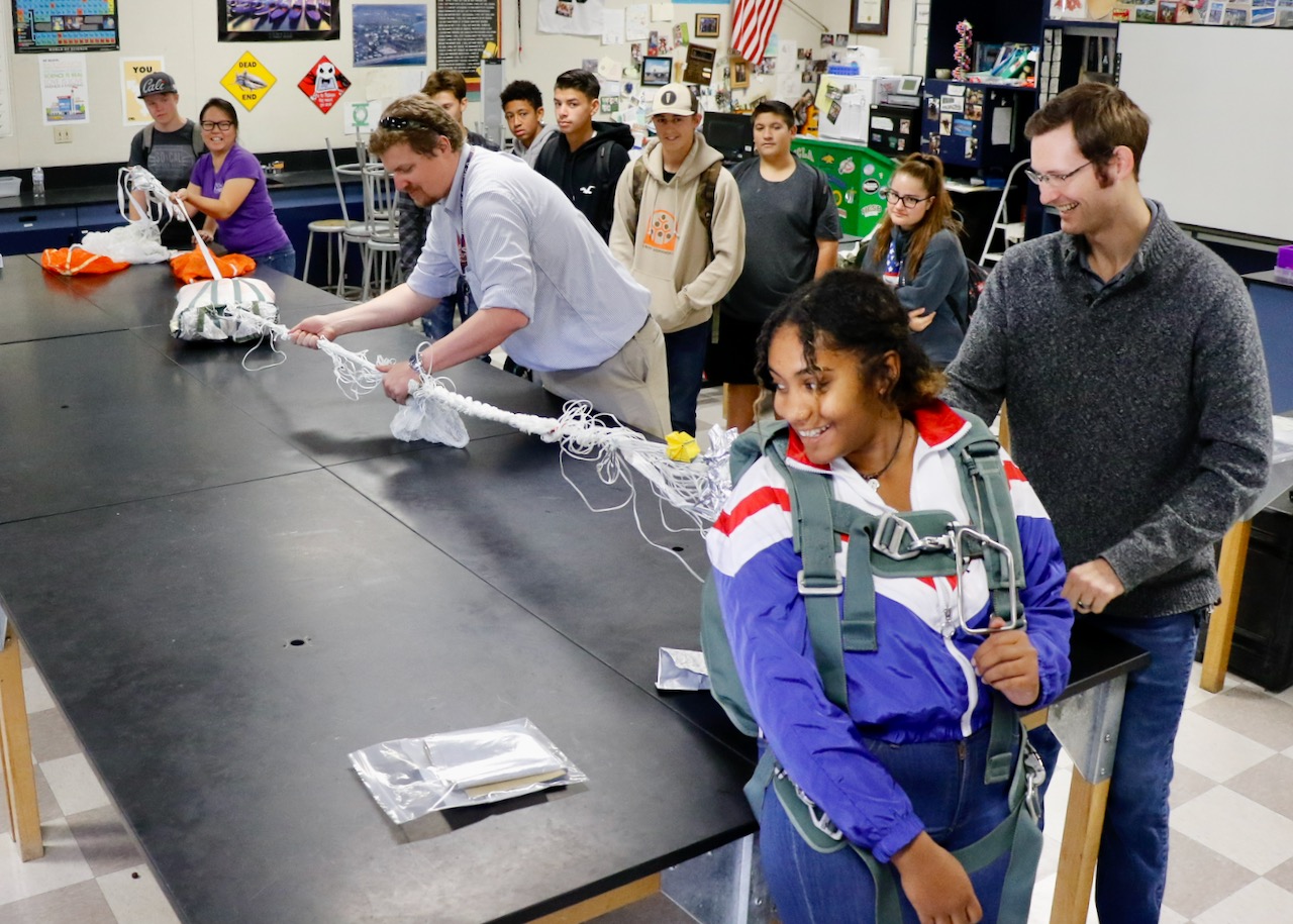 Jennifer Lam (in purple), Michael Petersen and Frederick Henderson attach a parachute to a Burroughs High School student and explain the intricacies of that during the BHS STEM day Nov. 8. (U.S. Navy photo by Paul Kakert)