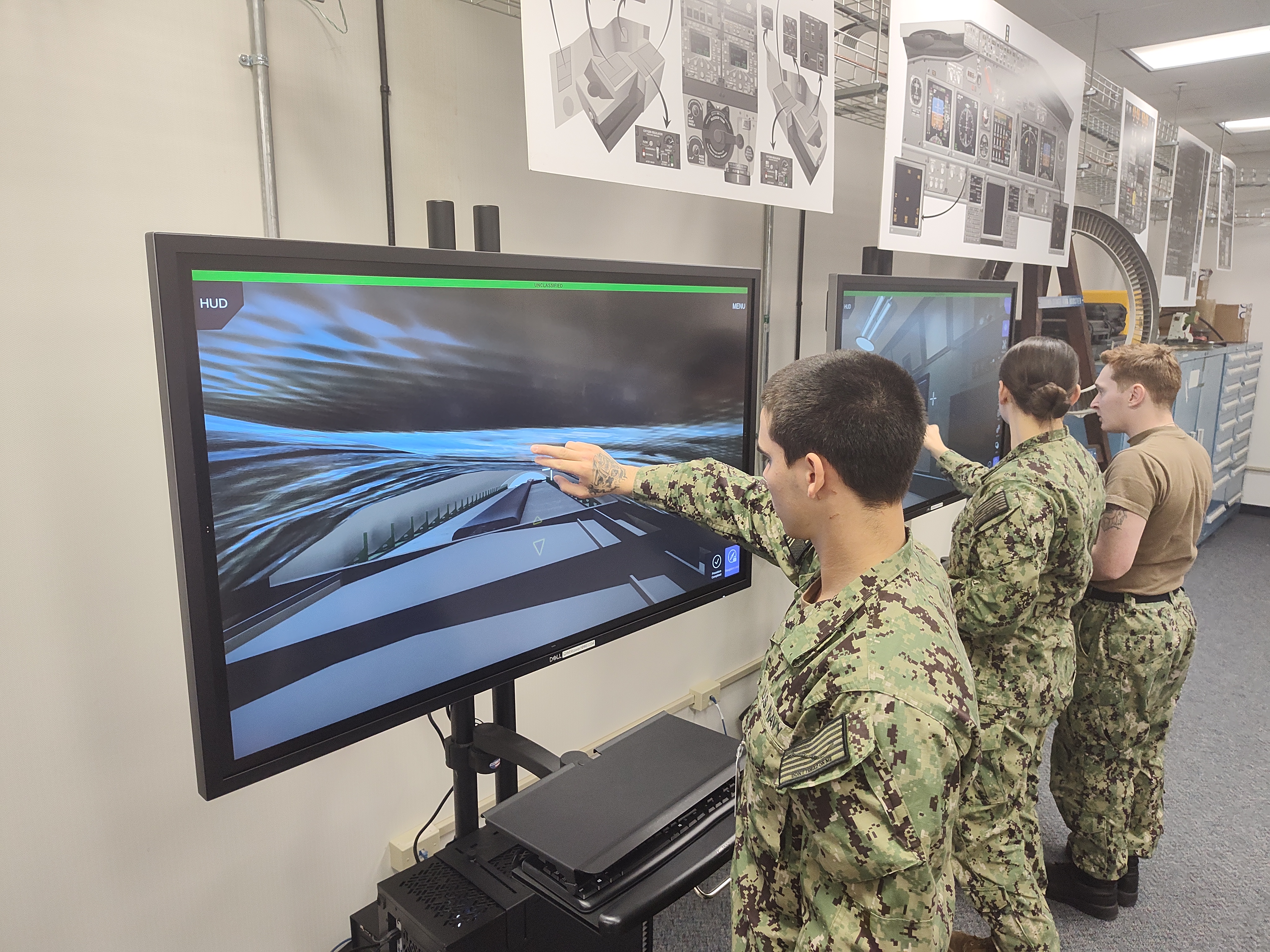 Three sailors in uniform training on virtual touch-screens