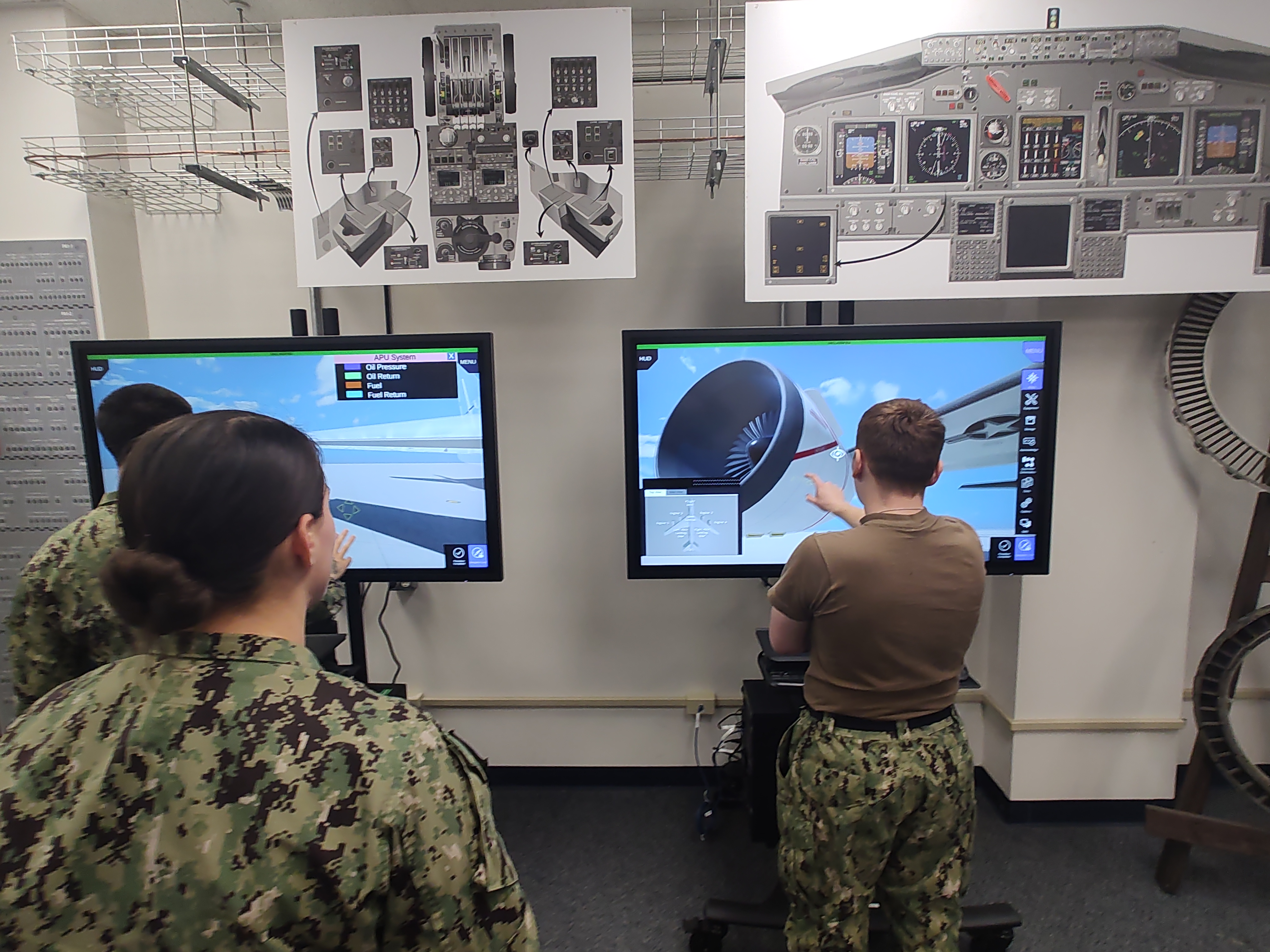 Three sailors in uniform conducting training on virtual touch-screens