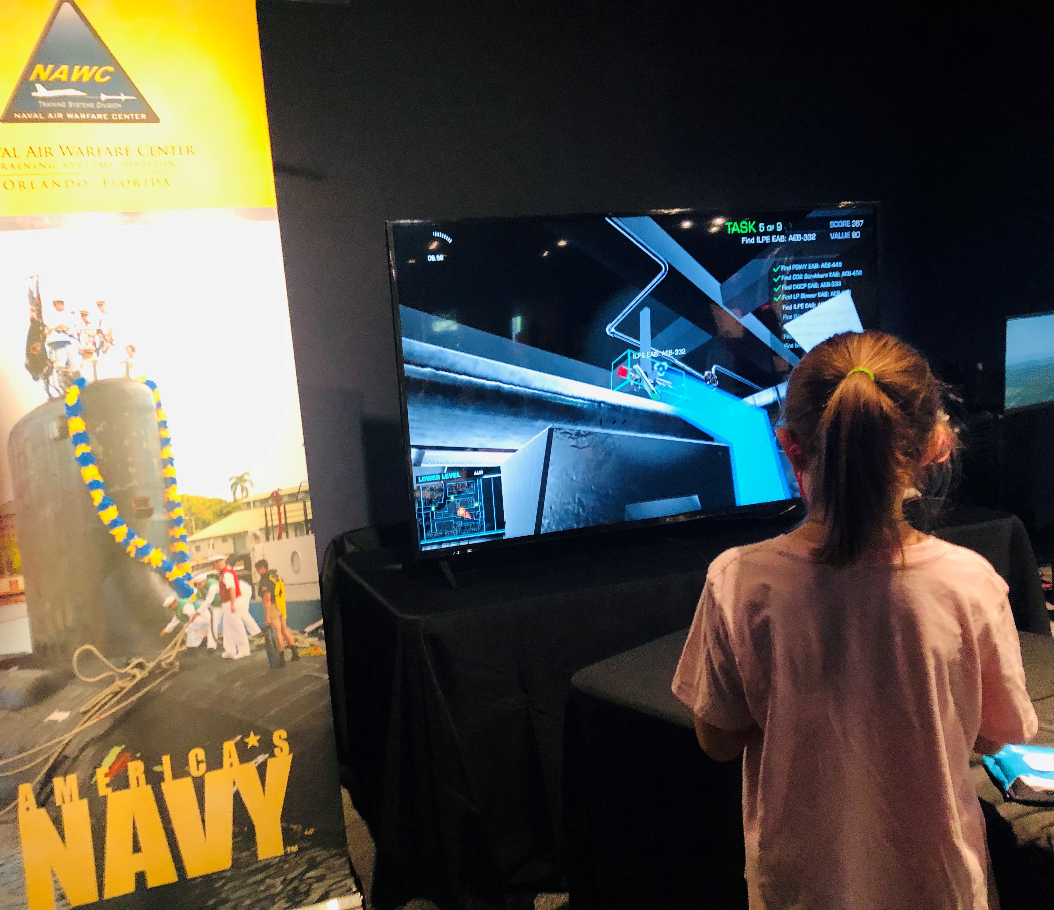Girl interacts with NAWCTSD STEM display at an event in Orlando, Florida.