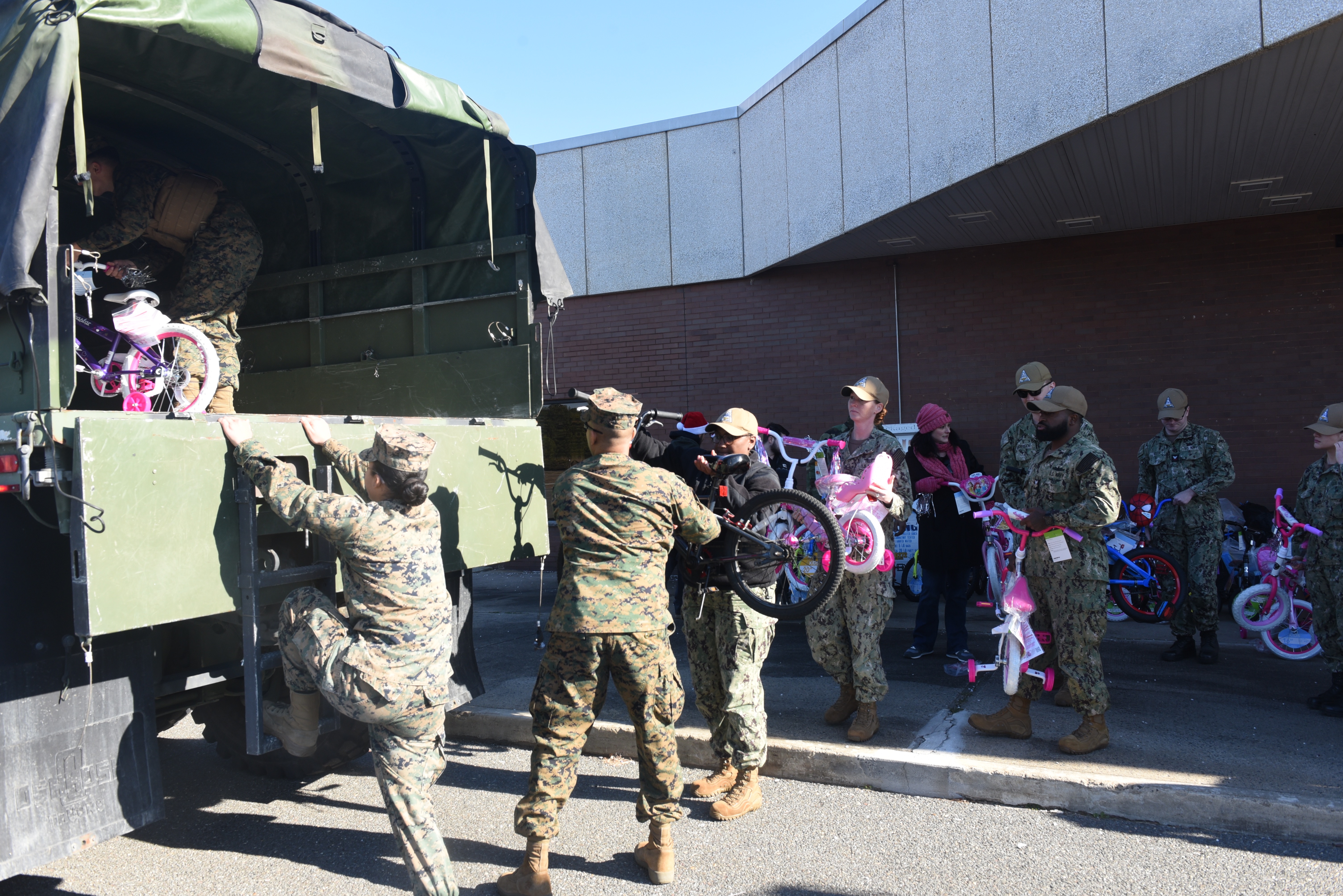 Volunteers work with Sailors from Joint Base McGuire Dix Lakehurst to fill trucks with toys for the annual Toys for Tots drive.