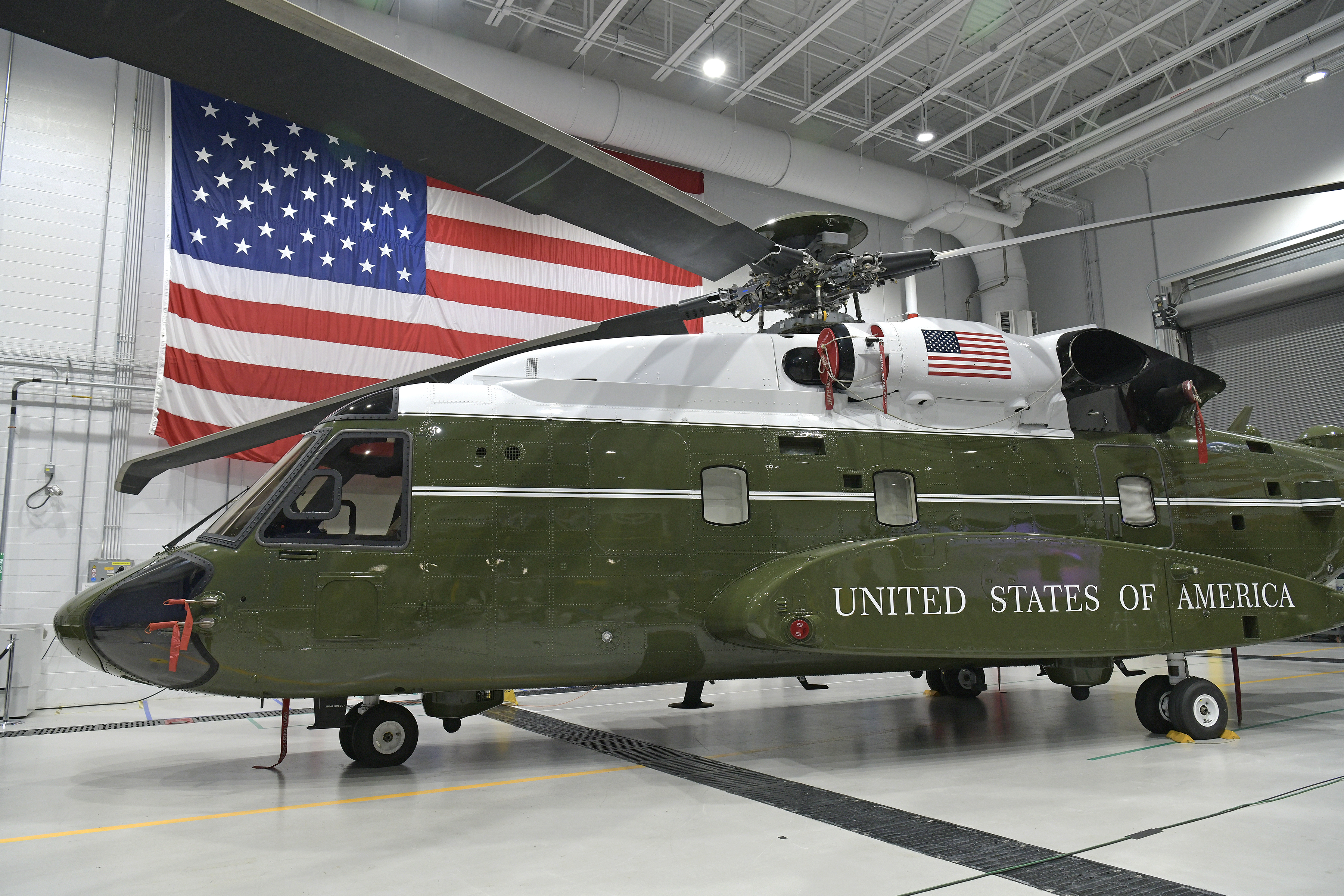 Helicopter in a hanger with the American flag behind it