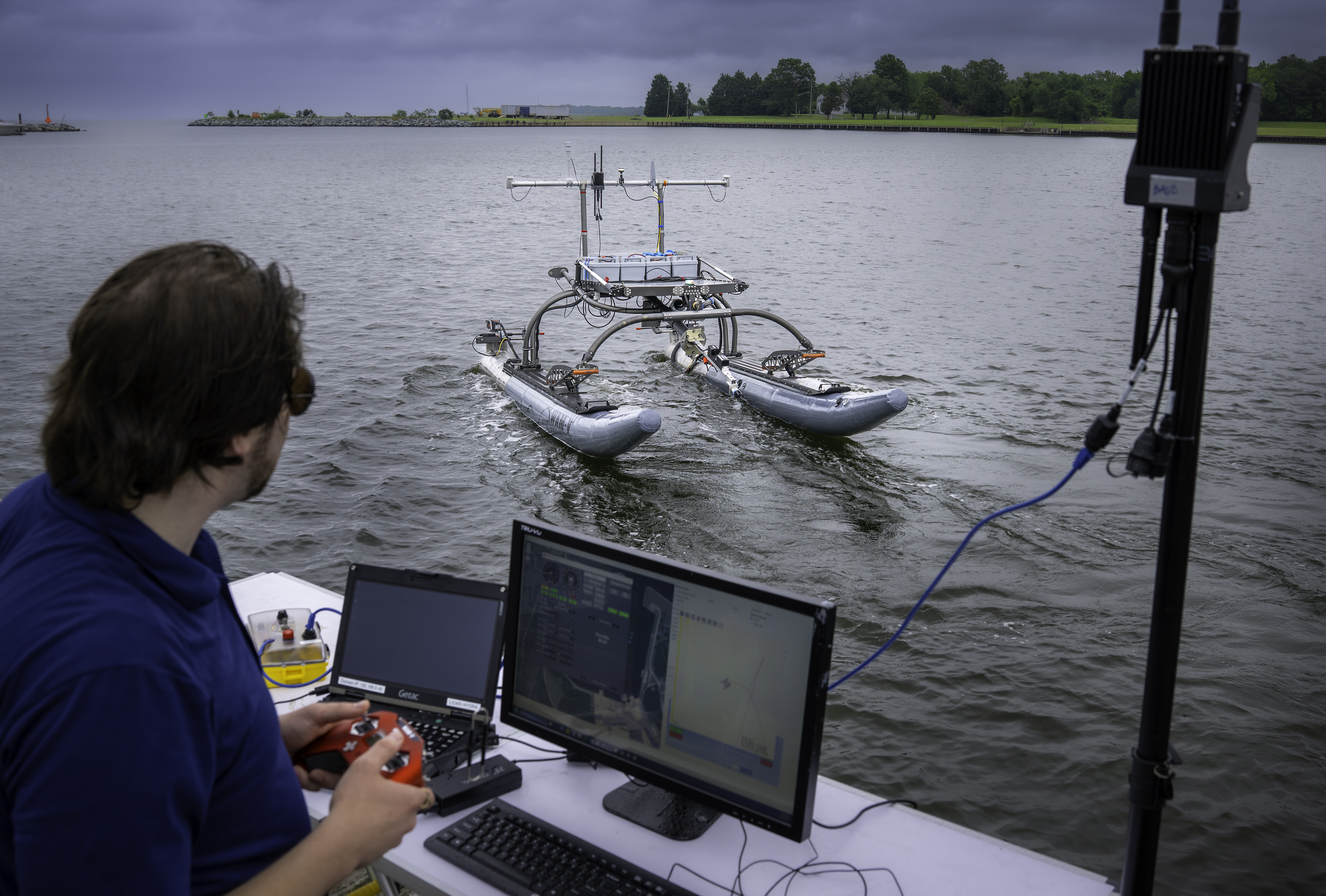 A man operates an unmanned system in the water with a game controller.