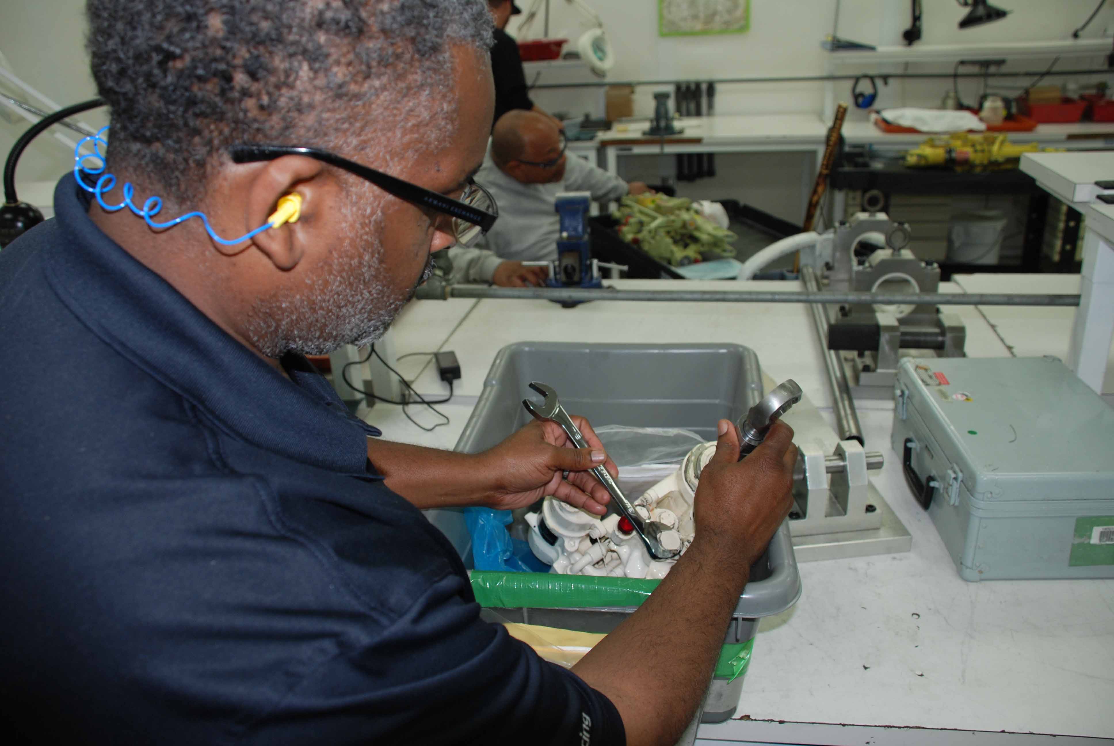 Pneudraulics systems mechanic Brett Lee disassembles a hydraulic servo system actuator assembly used on a Super Hornet aileron. (U.S. Navy photo)