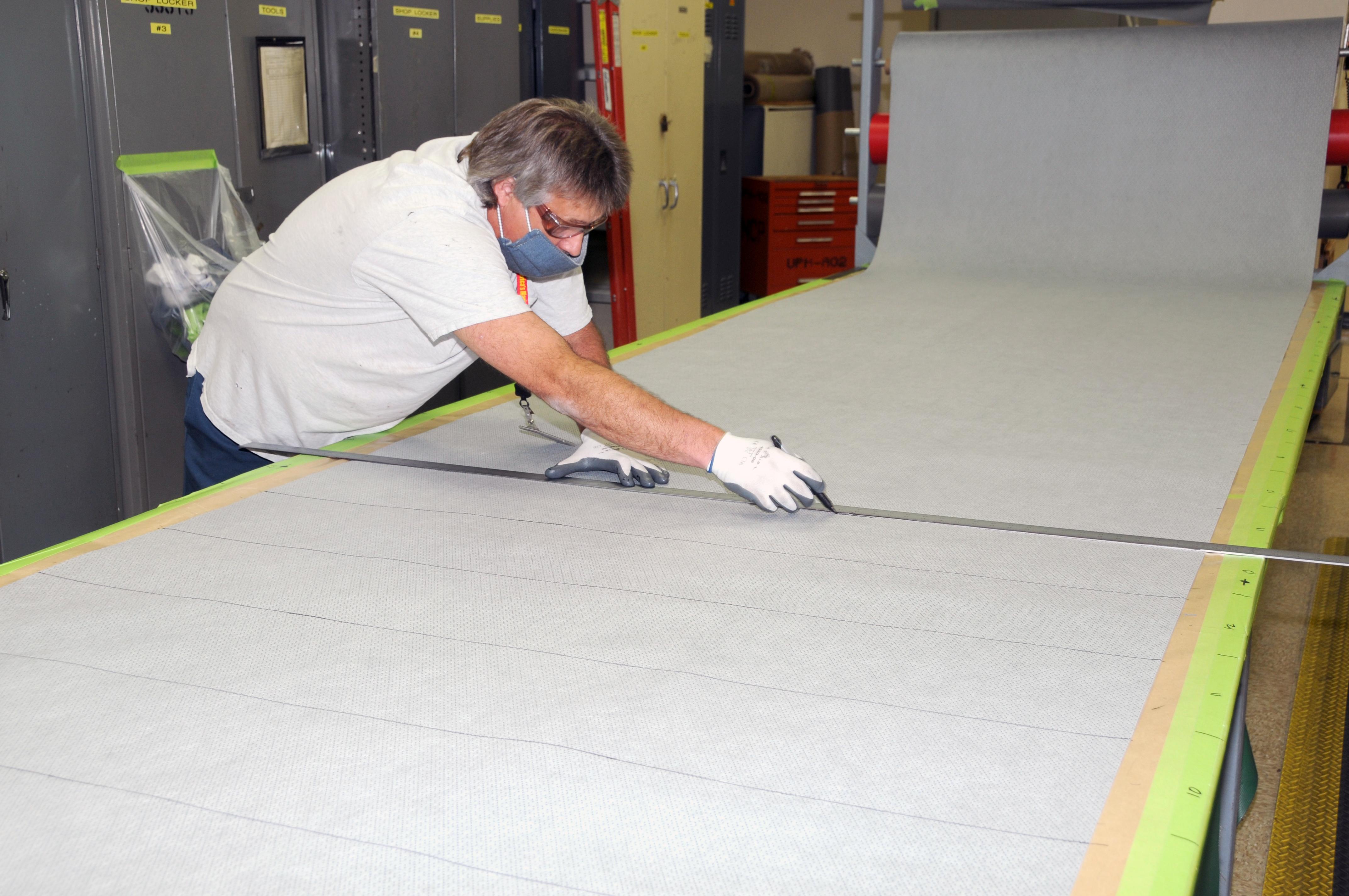 Man uses straight edge to cut fabric for cloth face coverings