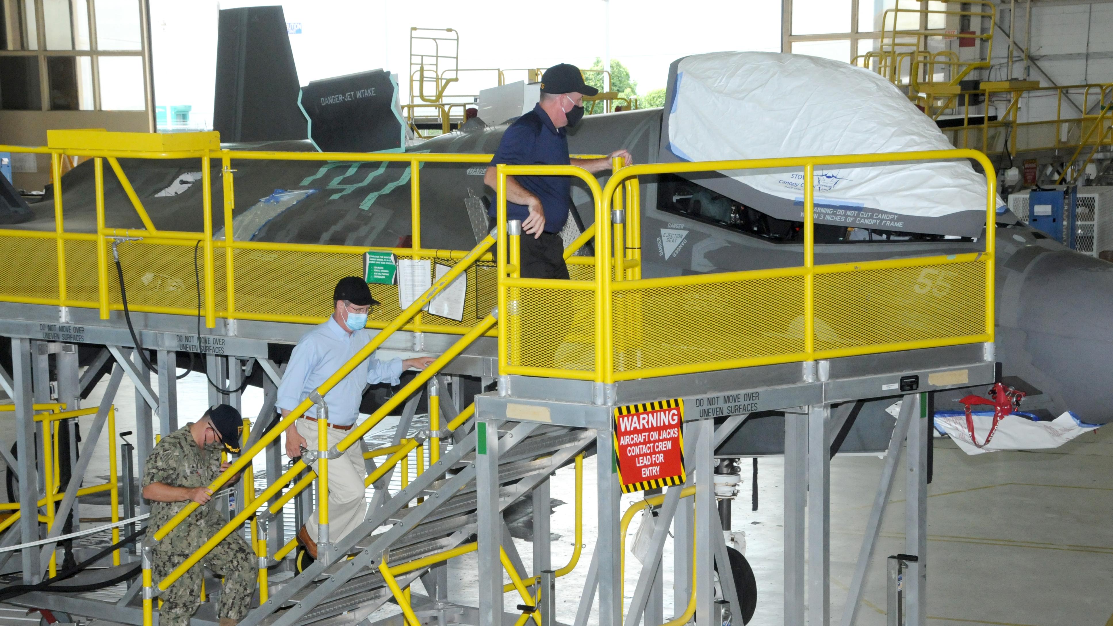 Three men climb stand to view F-35 aircraft