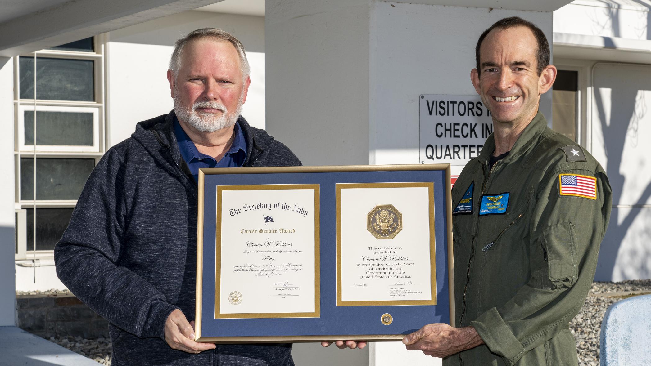 Clint Robbins poses with Rear Adm. Scott Dillon in front of the headquarters building in China Lake after receiving a 40-year length-of-service award on Jan. 6. (U.S. Navy photo by Ryan Smith)