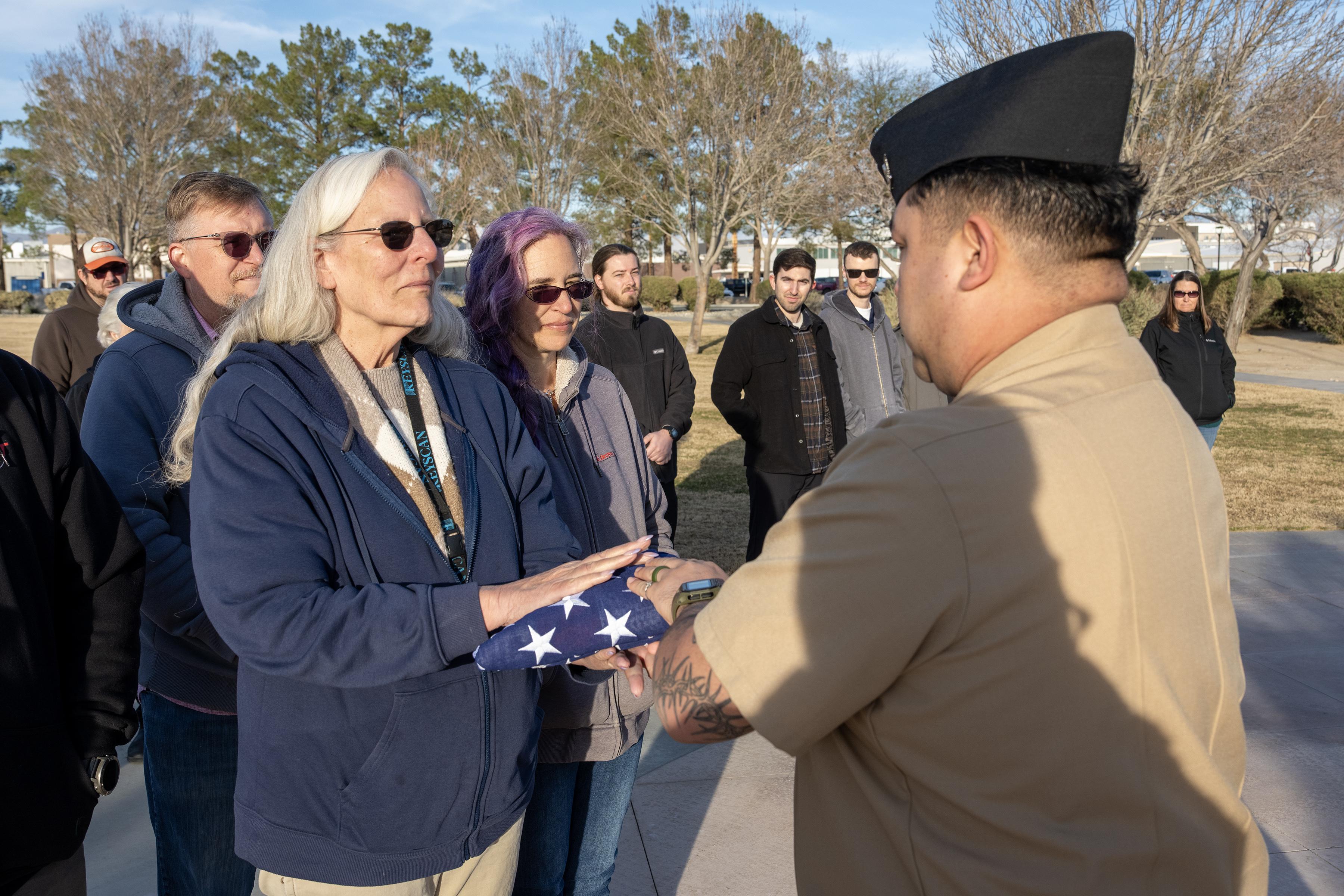 Surrounded by family and friends, Debbie Covey (left) is presented with a flag in honor of nearly 50 years of service to the government during a ceremony Jan.  28 in China Lake, Calif. (U.S. Navy photo by Ryan Smith) 