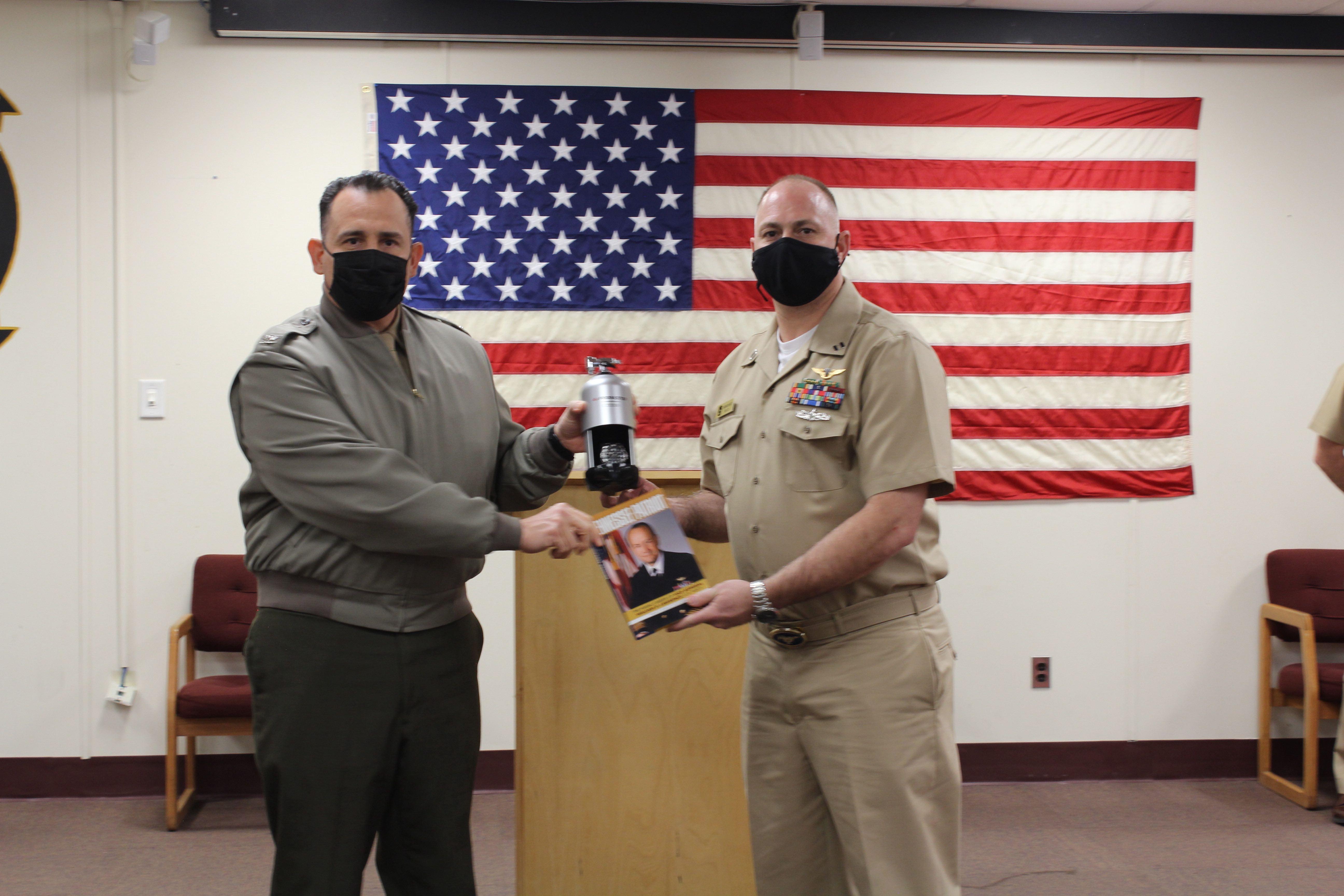 Col. Richard E. Marigliano, commander of Naval Test Wing Atlantic (NTWL), left, presents Air Test and Evaluation Squadron (HX) 21 maintenance officer Lt. Brandon Merchant with NTWL's Maintenance Officer of the Year award for 2020 during a ceremony on February 12 2021.