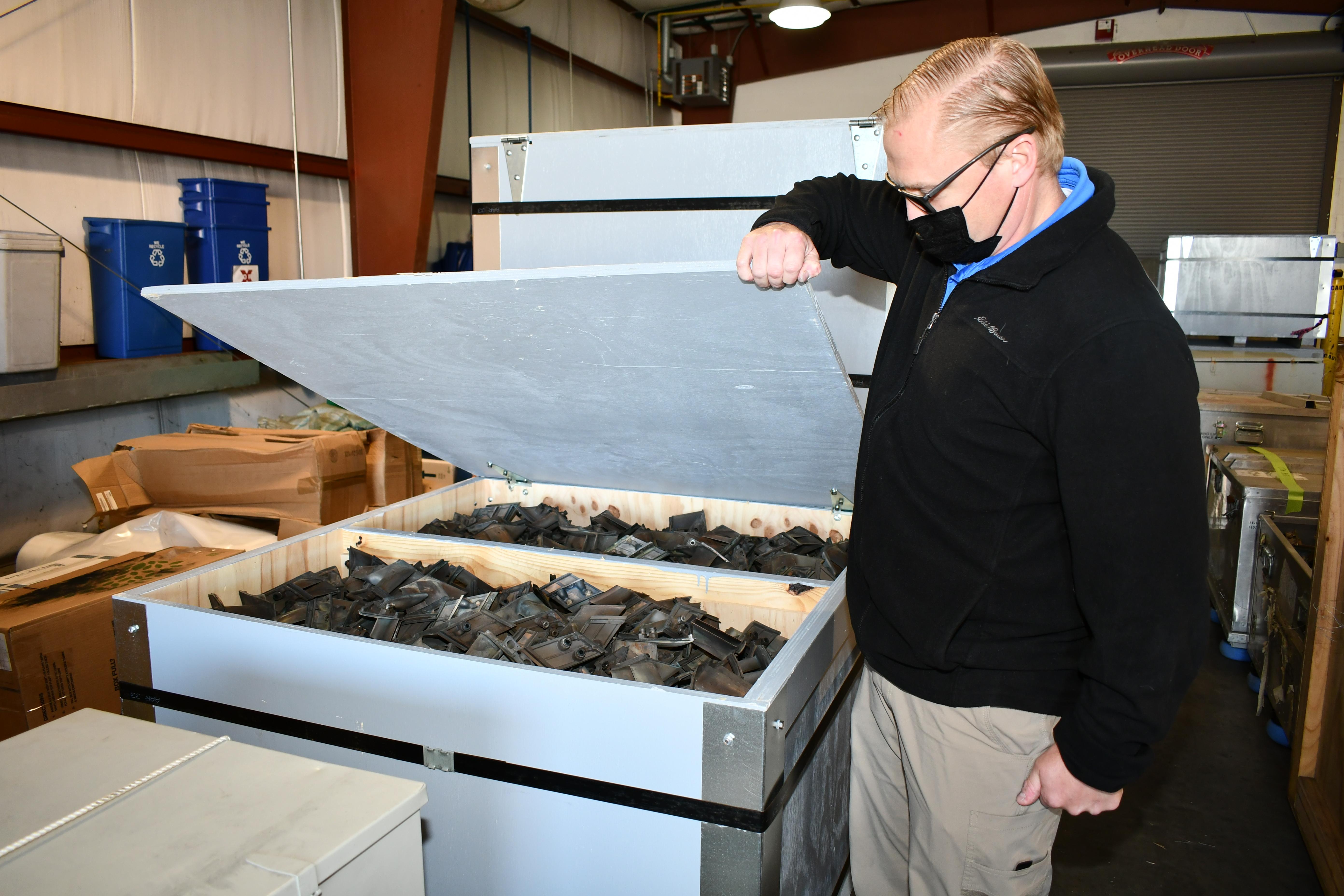 Man displays scrap parts in crate