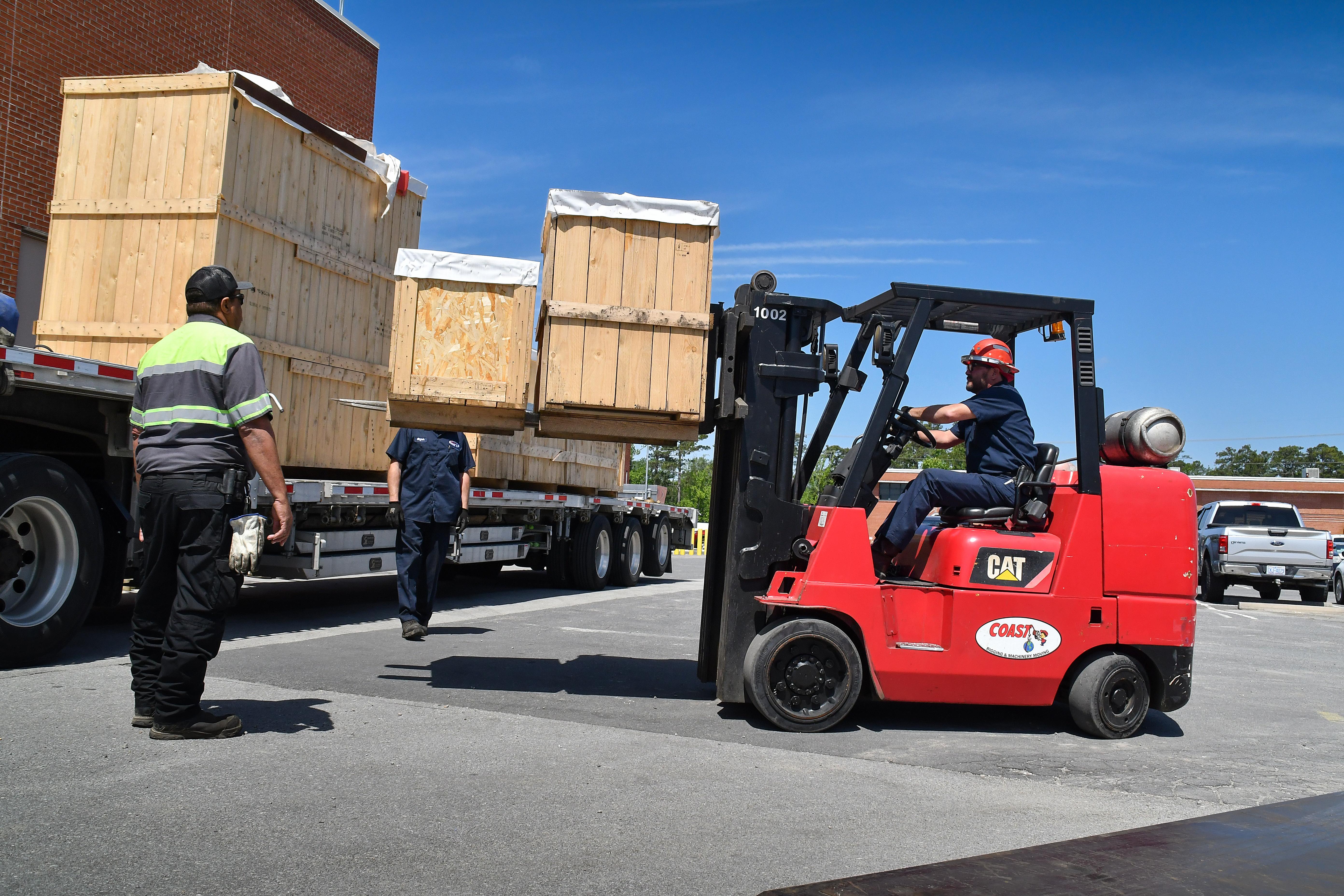 Rigging technicians unload a coordinate measuring machine (CMM) from a tractor trailer at Fleet Readiness Center East (FRCE). A CMM is a device that measures the geometry of physical objects by sensing points on the surface of the object with a probe. This machine is one of two new CMMs FRCE acquired capable of large-volume measurement. Depot officials say these additional machines will improve efficiency and reduce wait times caused by maintenance and equipment calibration.