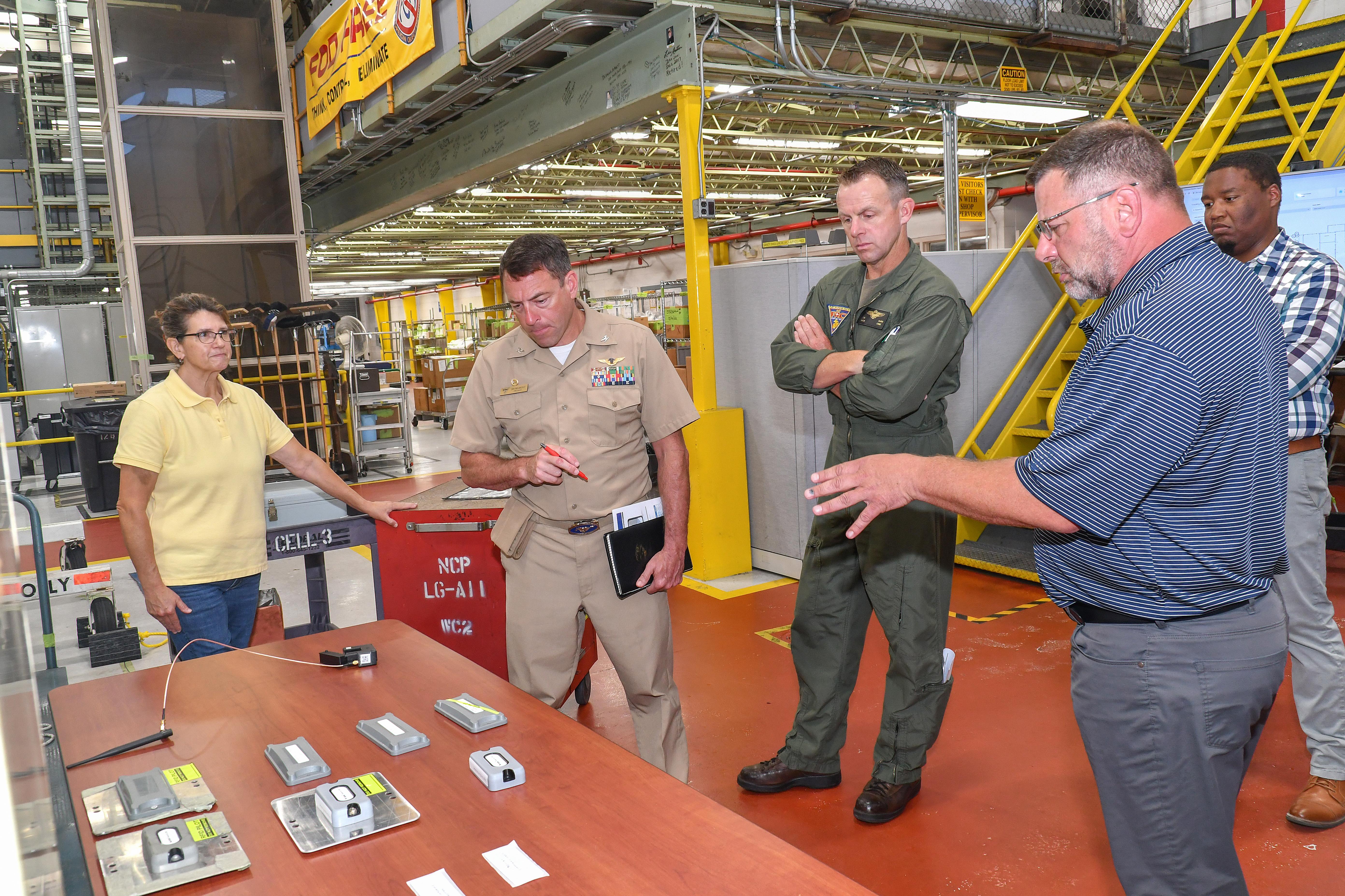 Jarred Burr, right, an electrical engineering technician at Fleet Readiness Center East (FRCE), briefs FRCE Commanding Officer Capt. James Belmont on radio frequency identification (RFID) technology tags tested and evaluated at the depot. FRCE recently demonstrated a successful proof of concept for a digital tracking system incorporating RFID and other technology. Depot officials say the system could boost efficiency and accountability within the depot’s workforce. 