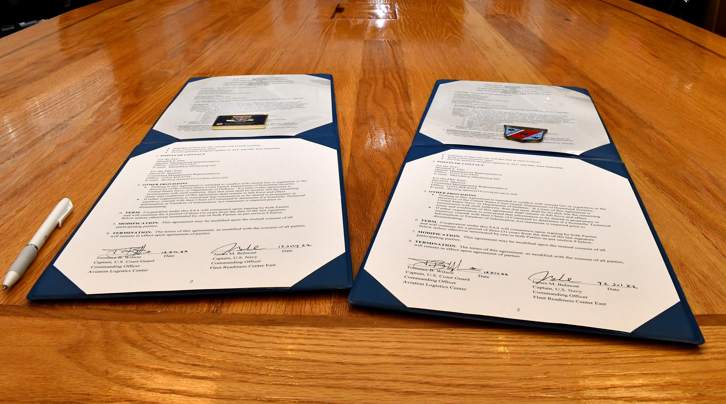 Two challenge coins sit on top of signed documents