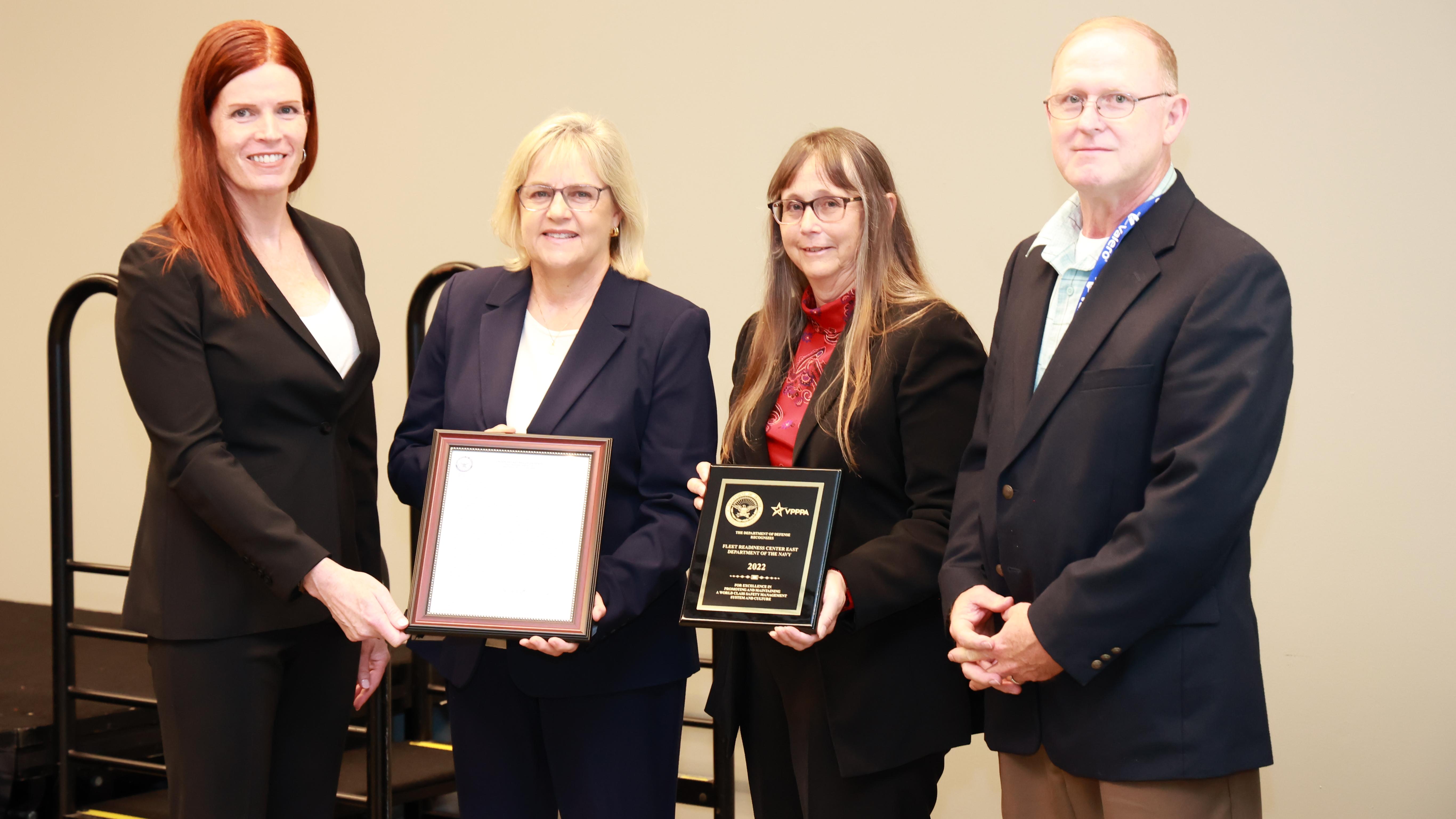 Group of four poses for photo with two plaques