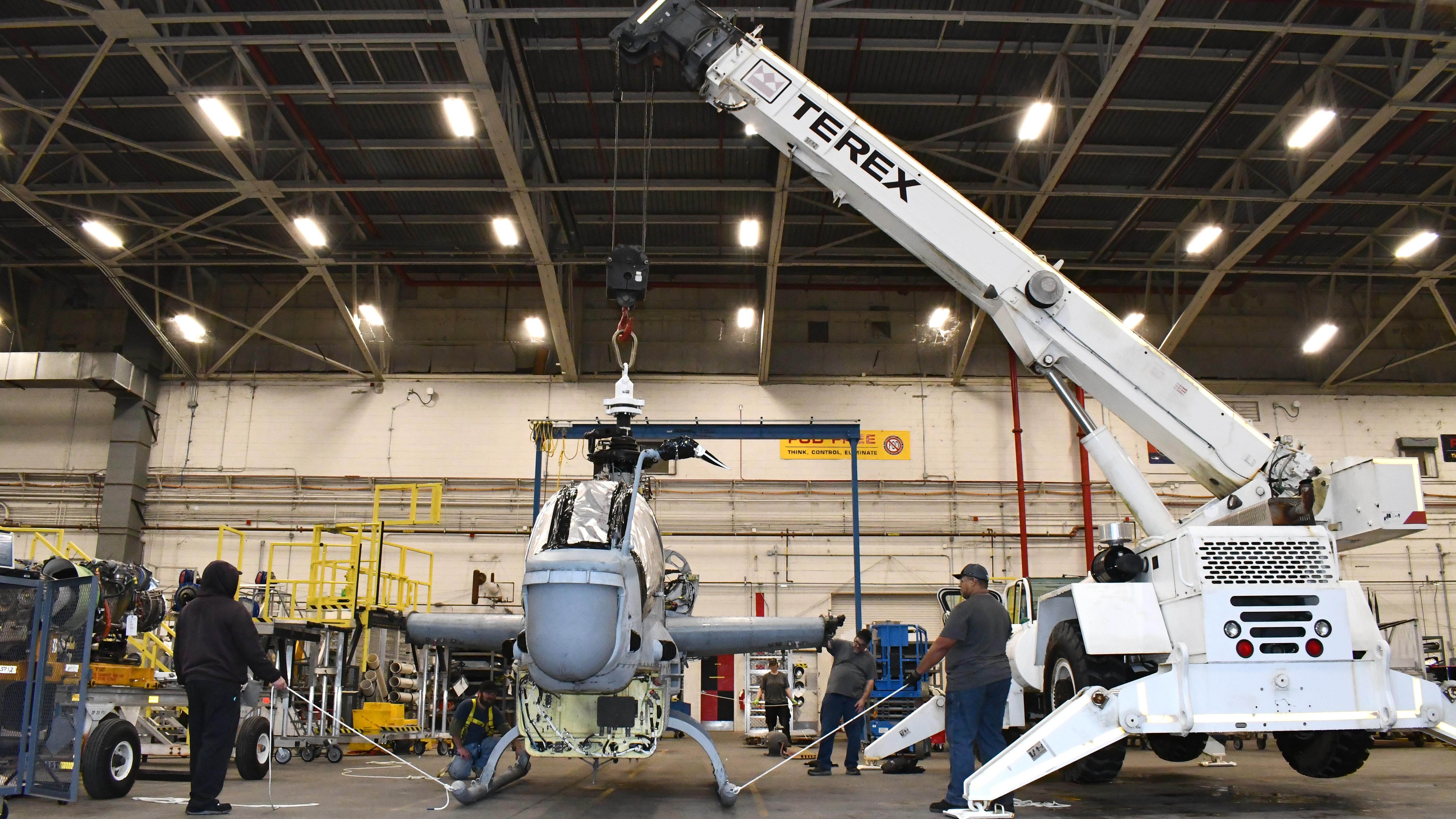 Workers prepare AH-1Z airframe for lift by crane