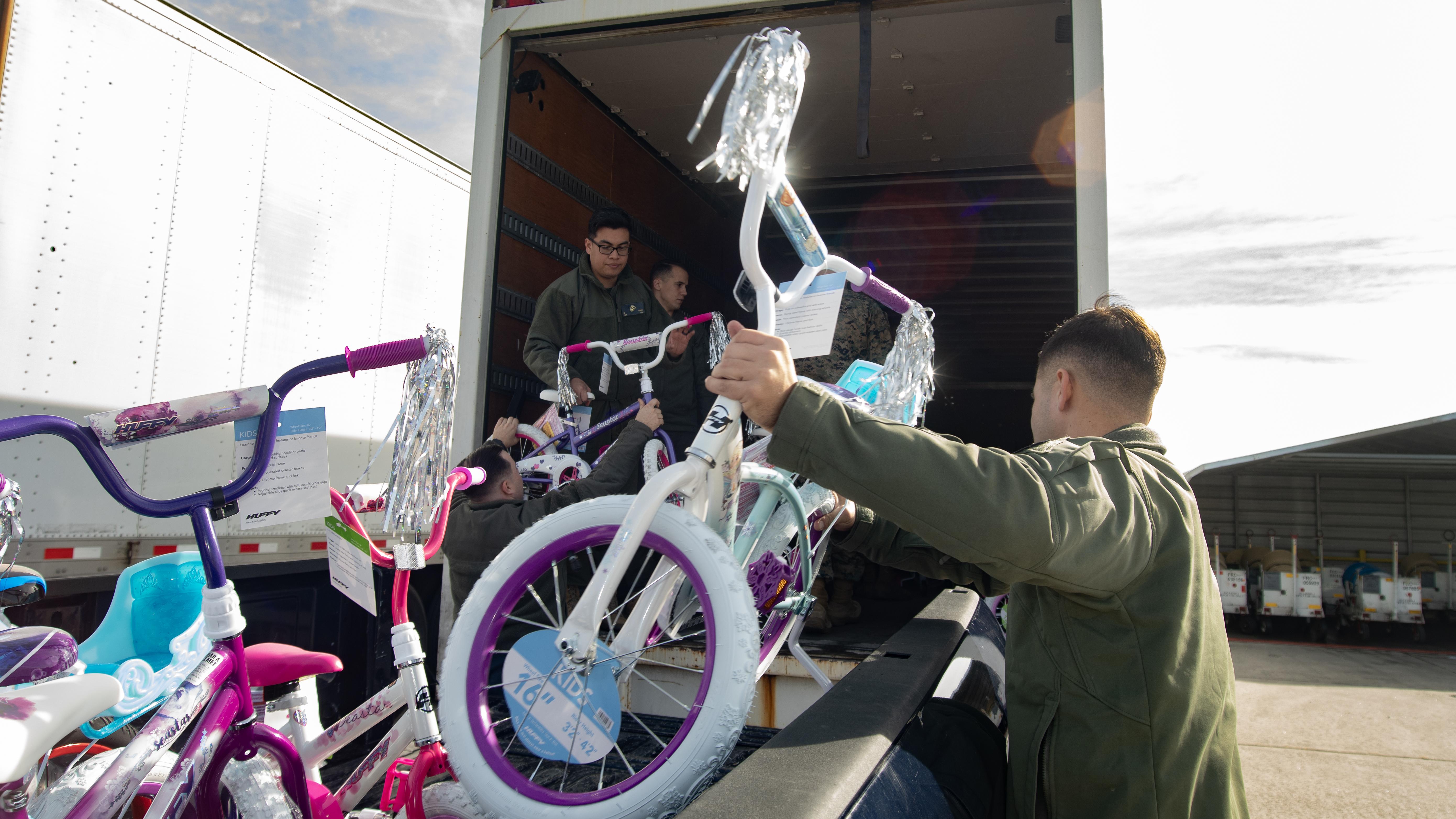 Man on right grabbing a children's bike to put into semi-trailer 