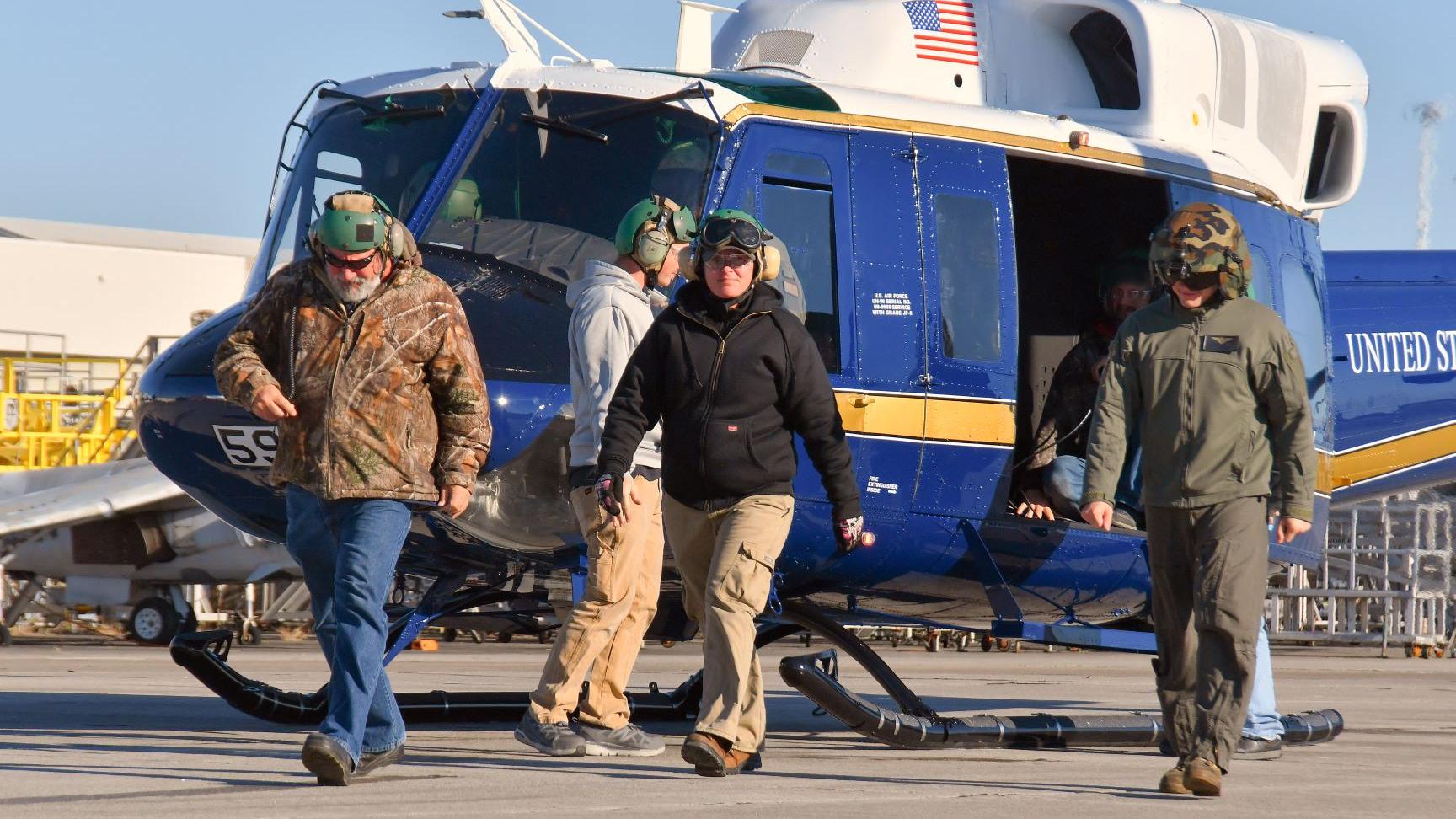 Marine and civilian ground walk in front of Air Force UH-1N helicopter following functional check flight 