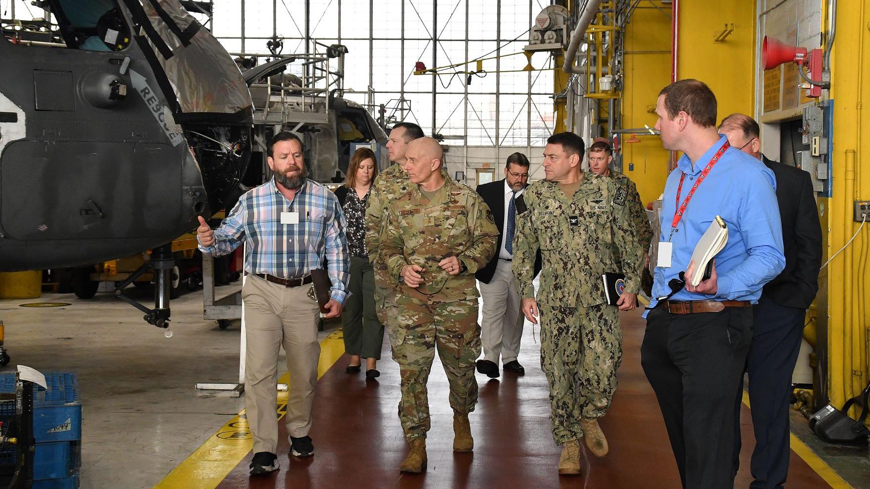 Group of military officials walks down aisle in aircraft hangar