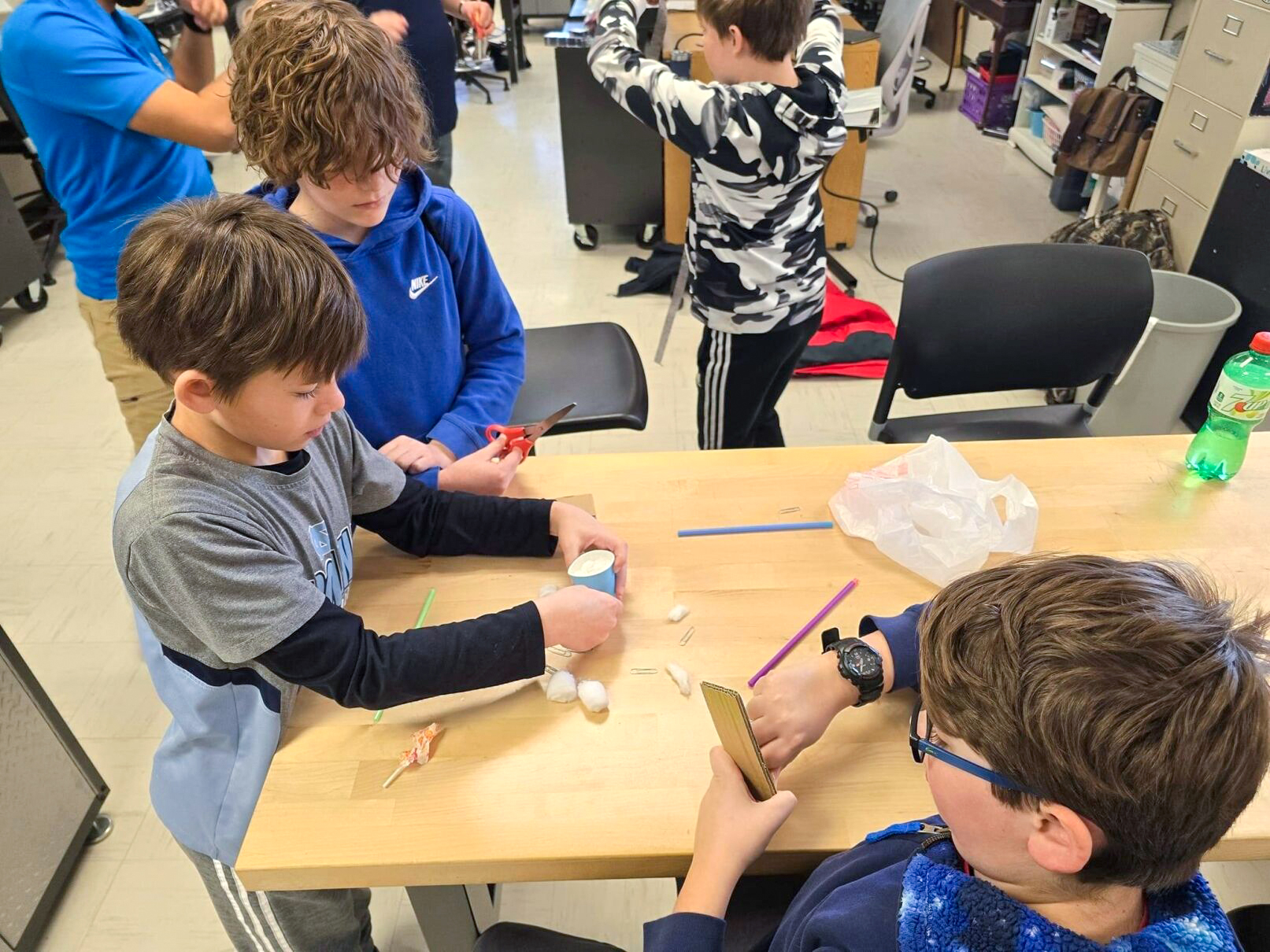 Three students work on project at a table in a classroom 