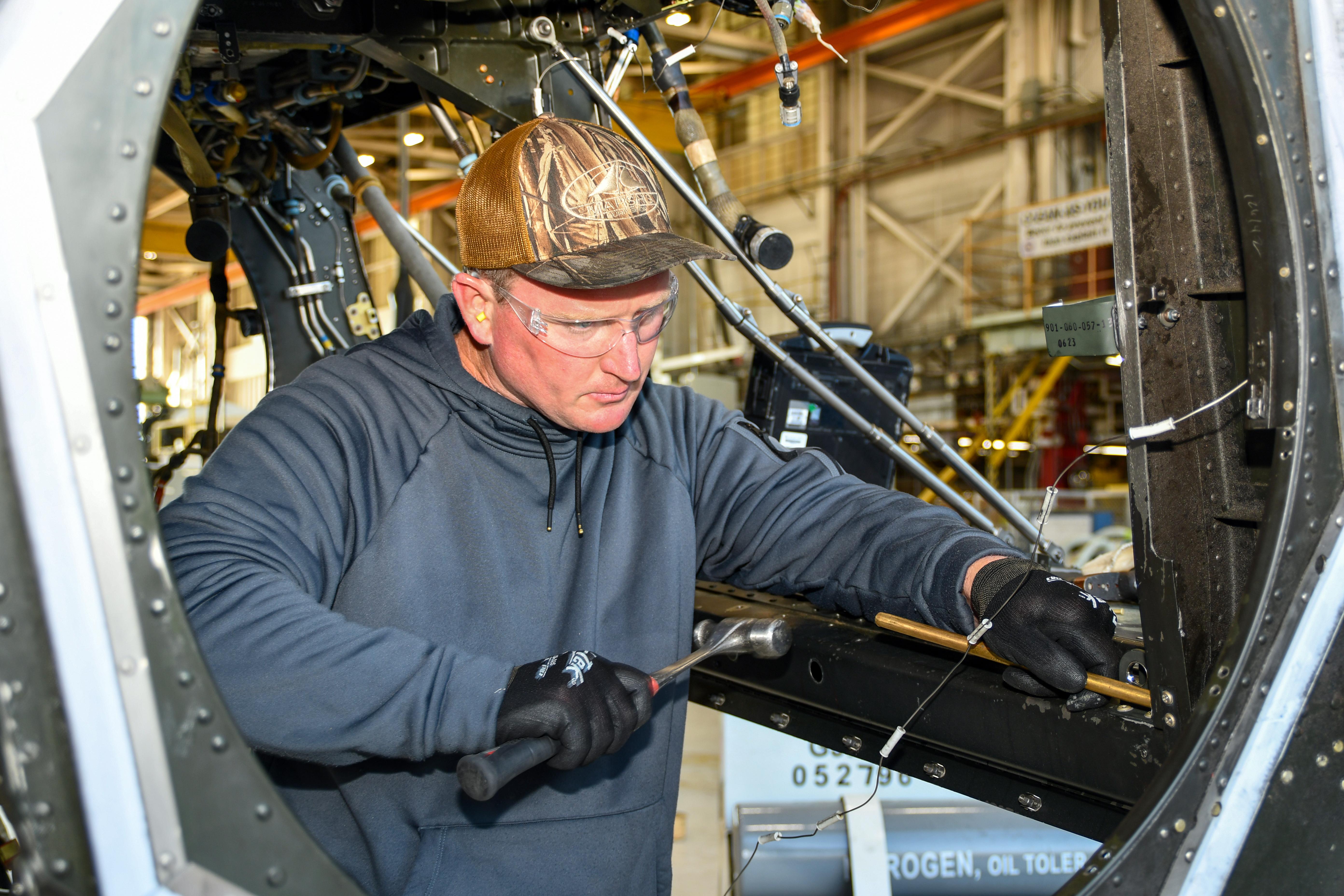 Man using hammer to work on metal aircraft frame