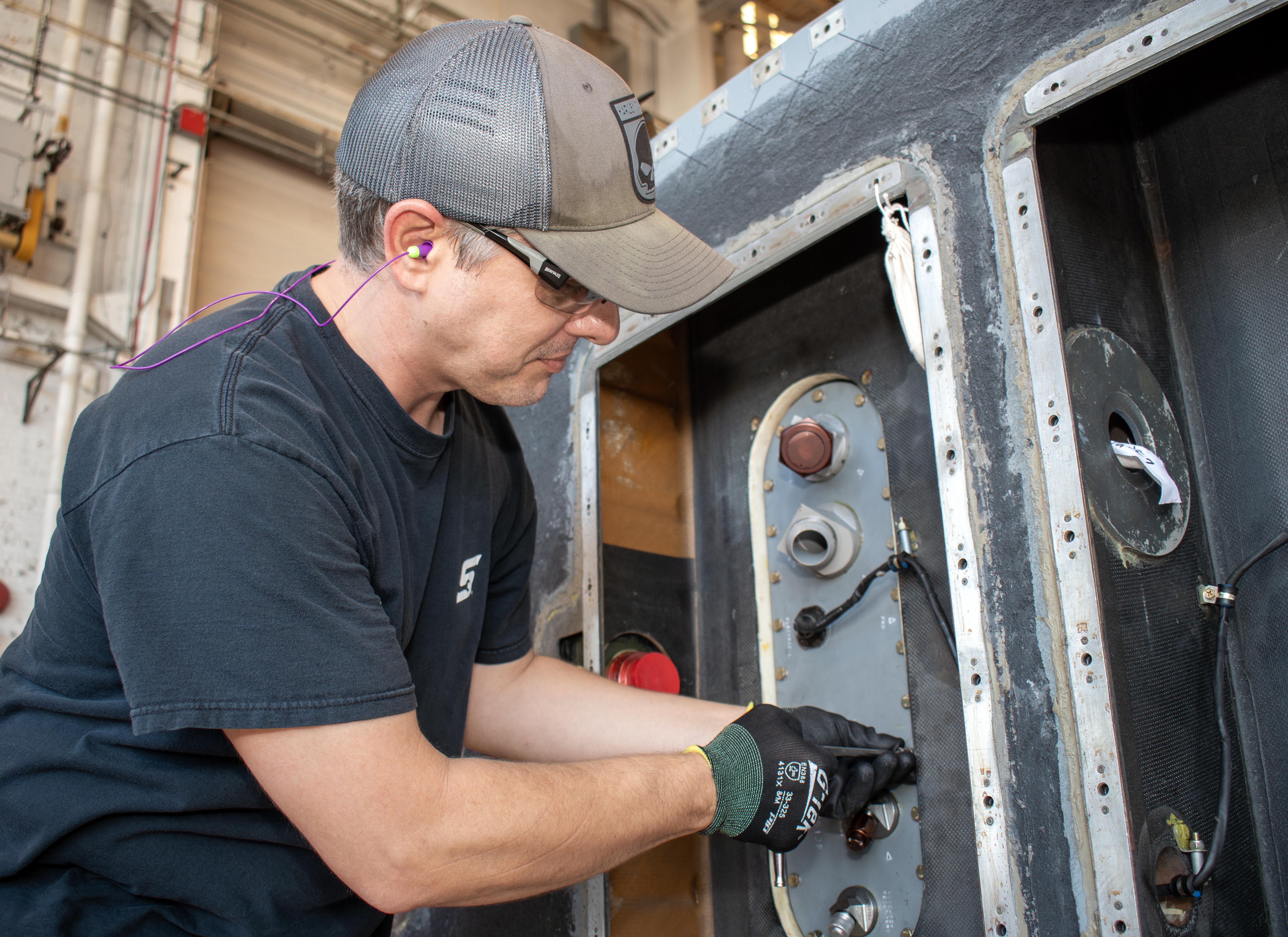 Man performing maintenance on metal panel