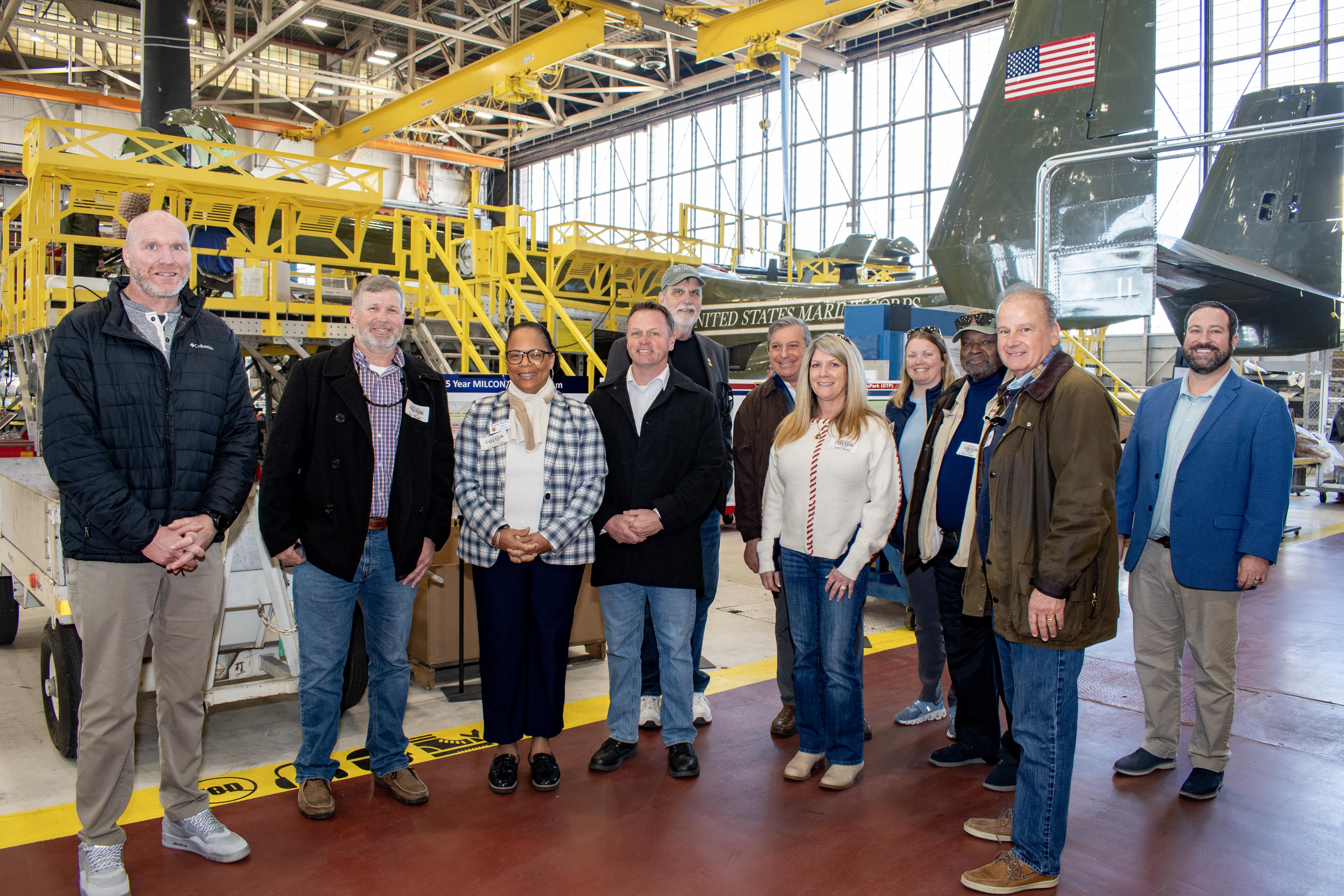 Group photo of people standing on red isle in an aircraft hangar