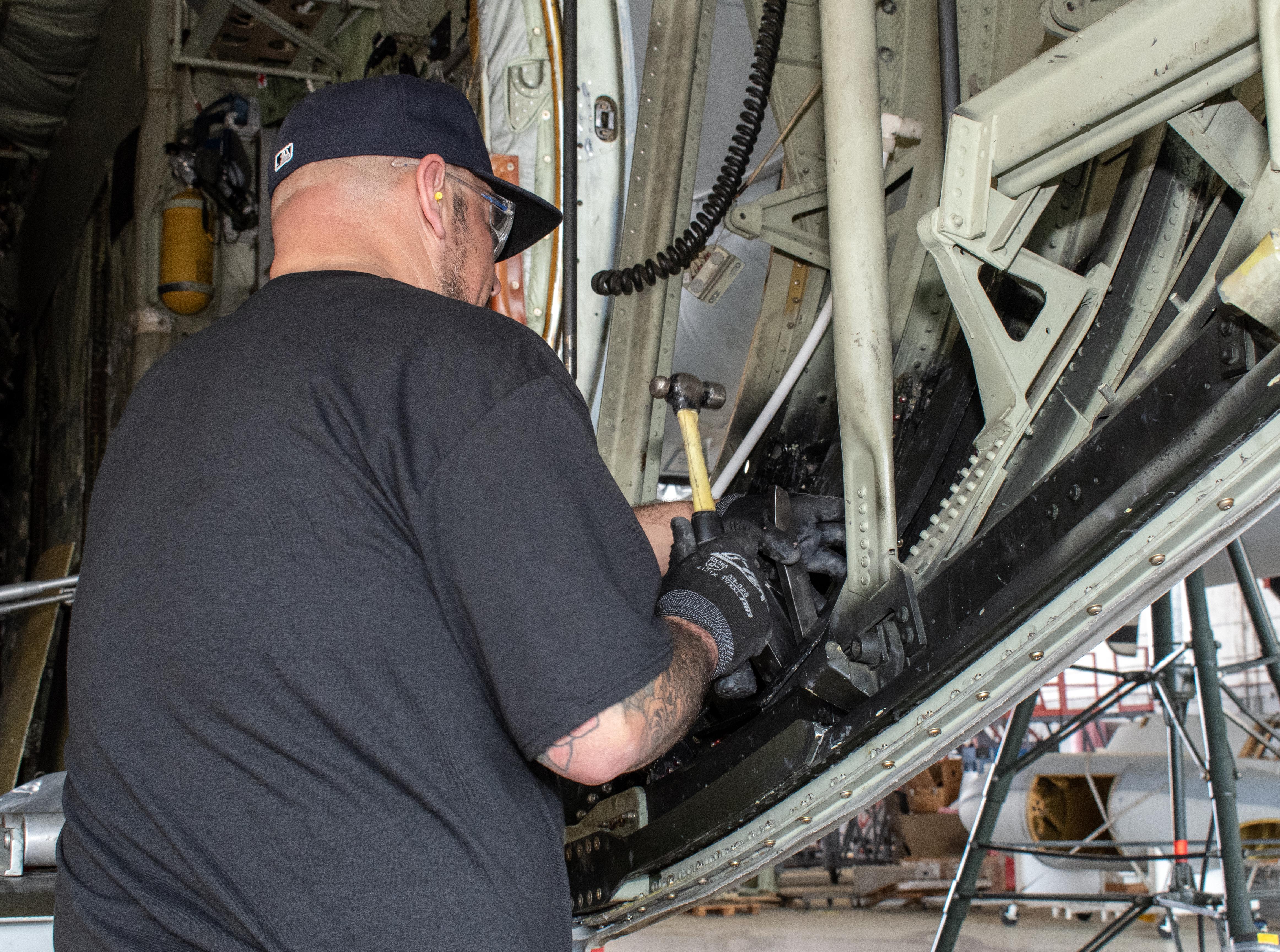 man in black shirt works on inside of aircraft