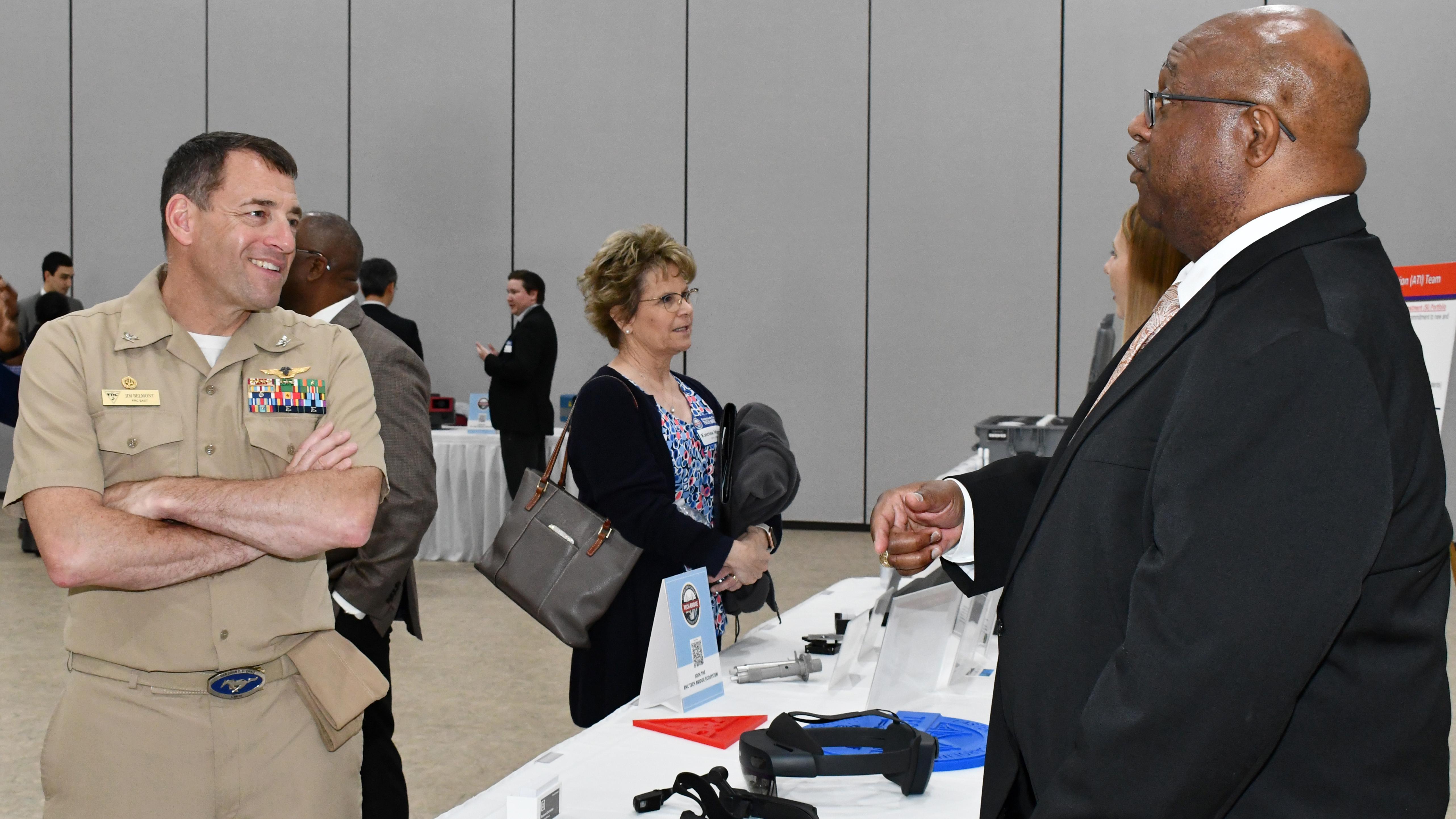 Two men speak across expo table