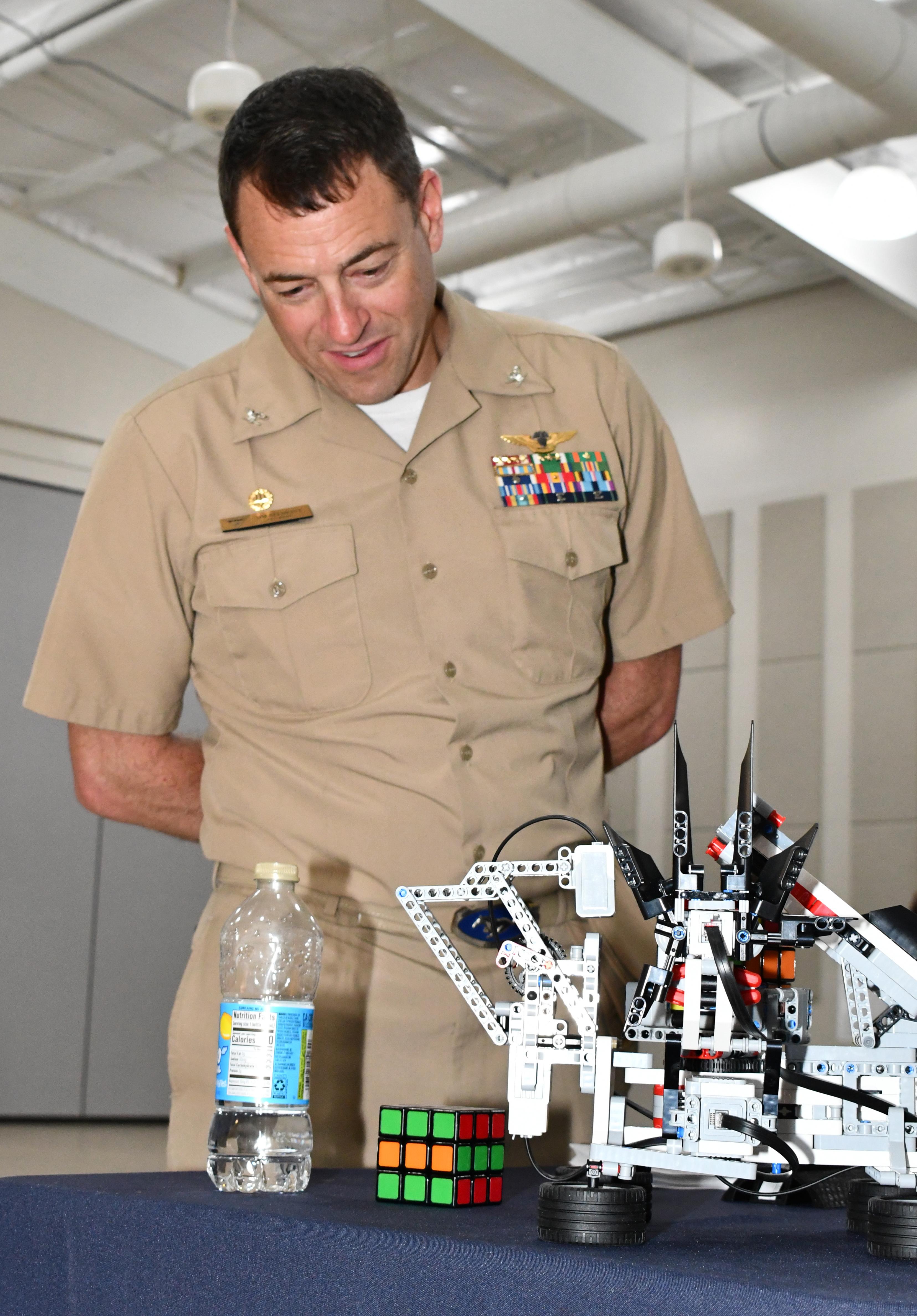 Military officer watches puzzle cube-solving robot