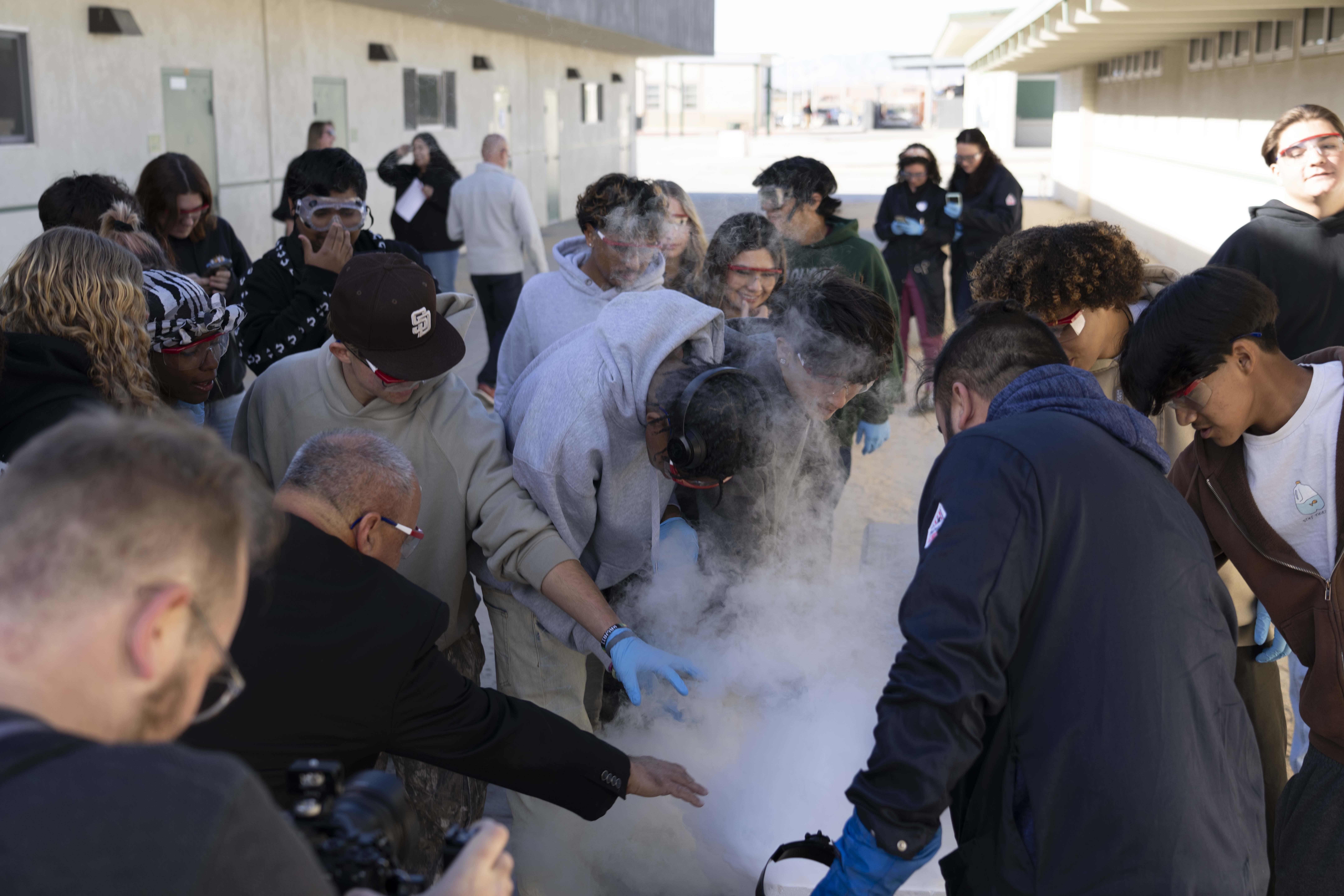 Naval Air Warfare Center Weapons Division Executive Director Dan Carreño (second from left) joins a group of students during a liquid nitrogen experiment performed by NAWCWD Chemist Dr. Patrick Fedick (right) during a Burroughs High School STEM event last fall in Ridgecrest, Calif.  (U.S. Navy photo by Ryan Smith)