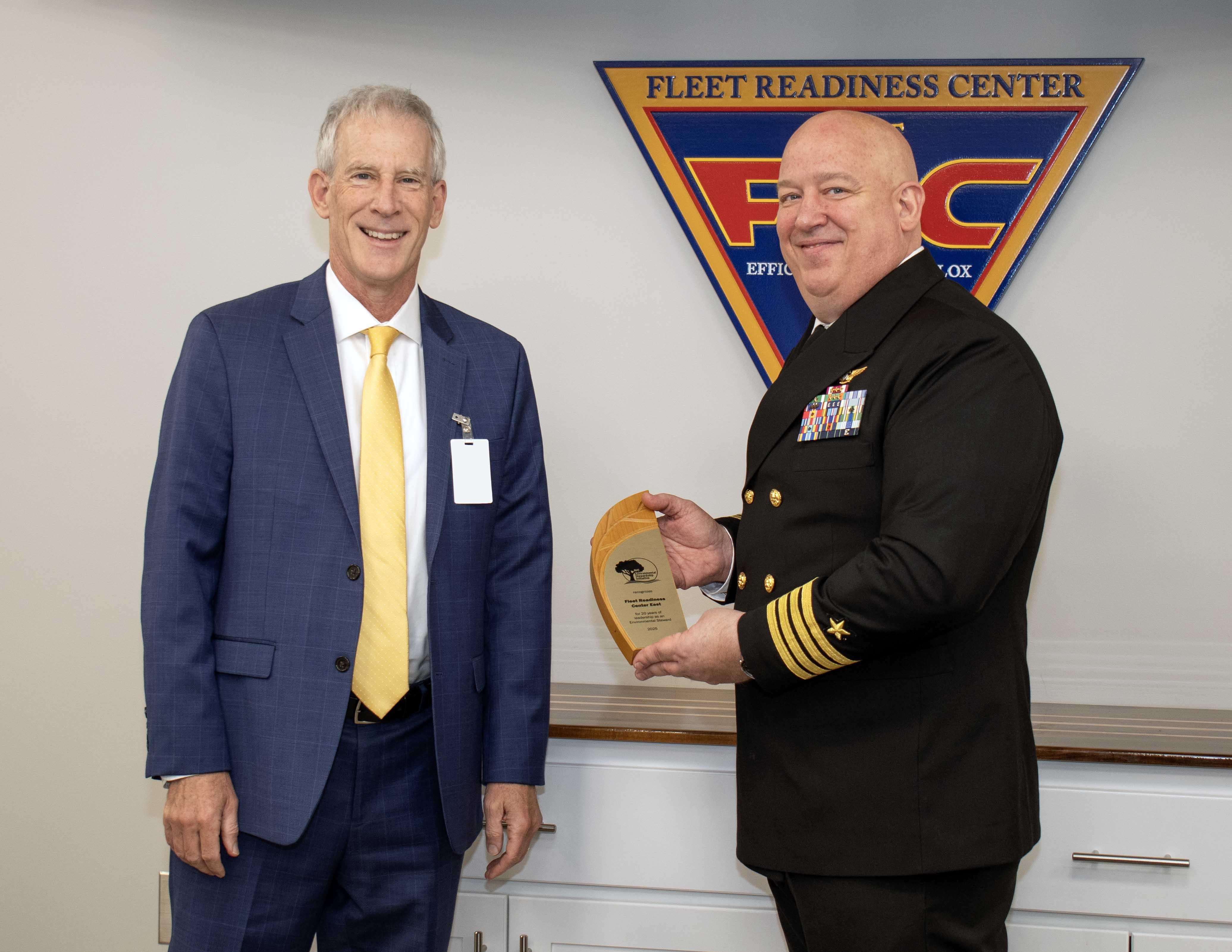 Sailor poses for award photo with man in blue suit