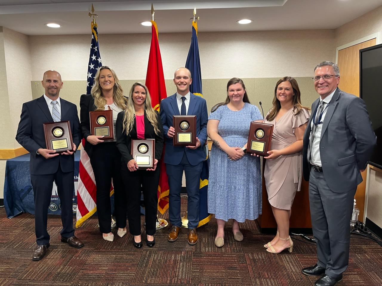 pictured: NAVAIR award-winners: (left to right) Jason Tiede,  Tess Butner, Mandy Miedzinski, Tyler Vallandingham,  Shelbee Mattingly, Kari O’Brien,  Pat Lowien, NAVAIR comptroller 